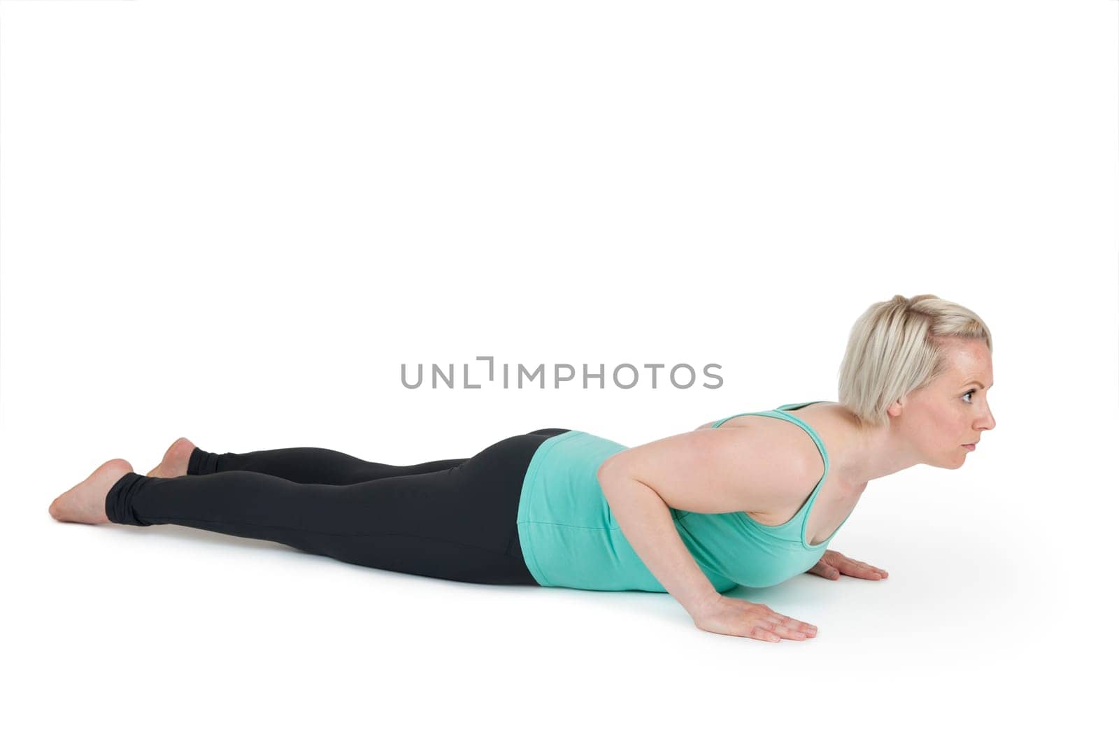 Full-body view of a young blonde woman during the yoga exercises "Cobra"" against a white background with a slight shadow"