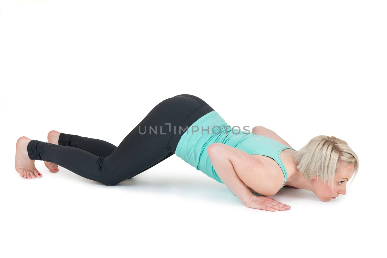Full-body view of a young blonde woman during the yoga exercises "Cobra"" against a white background with a slight shadow"