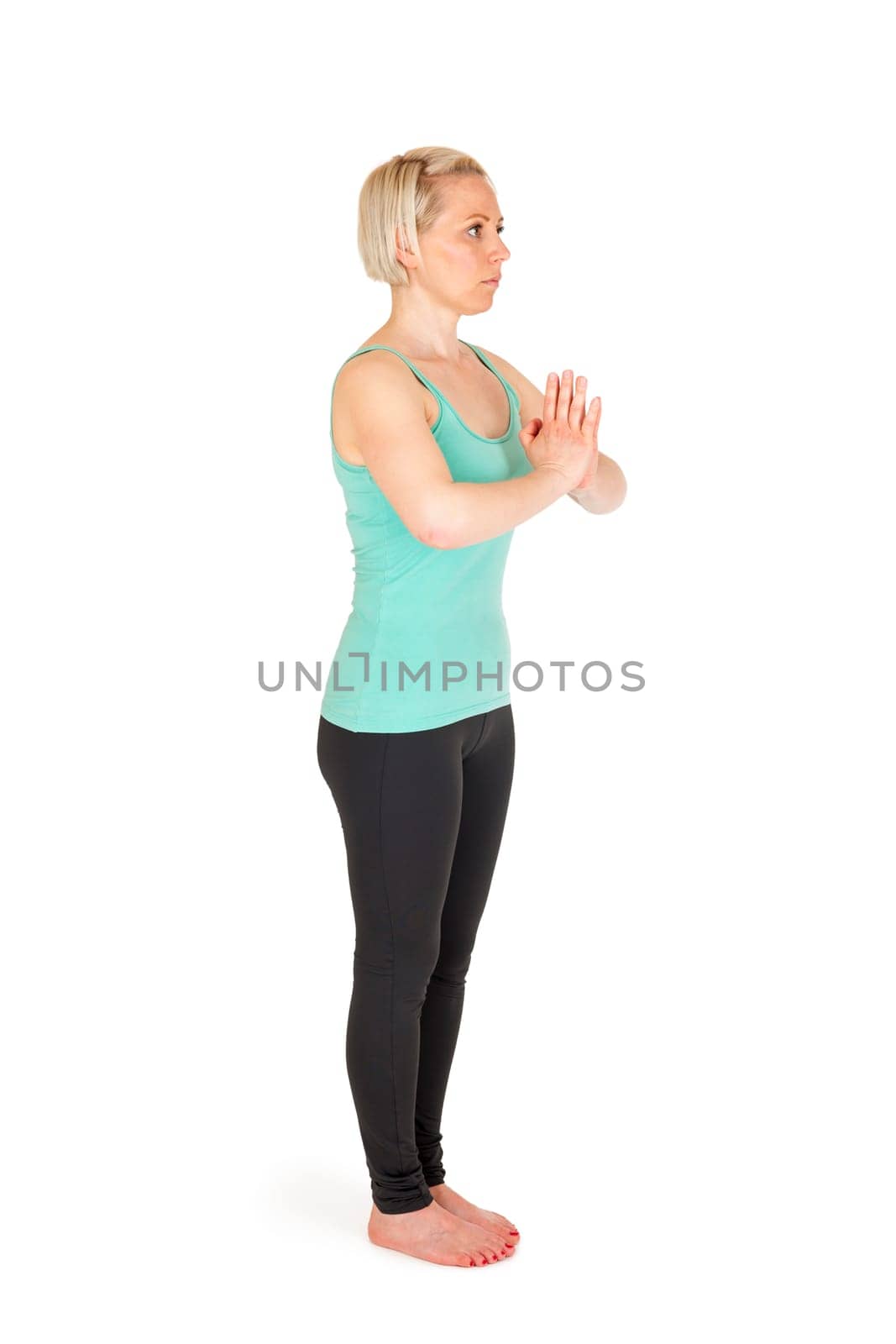 Full-body view of a young blonde woman during yoga exercise "Standing Prevention"" Step 1 against a white background with a slight shadow"