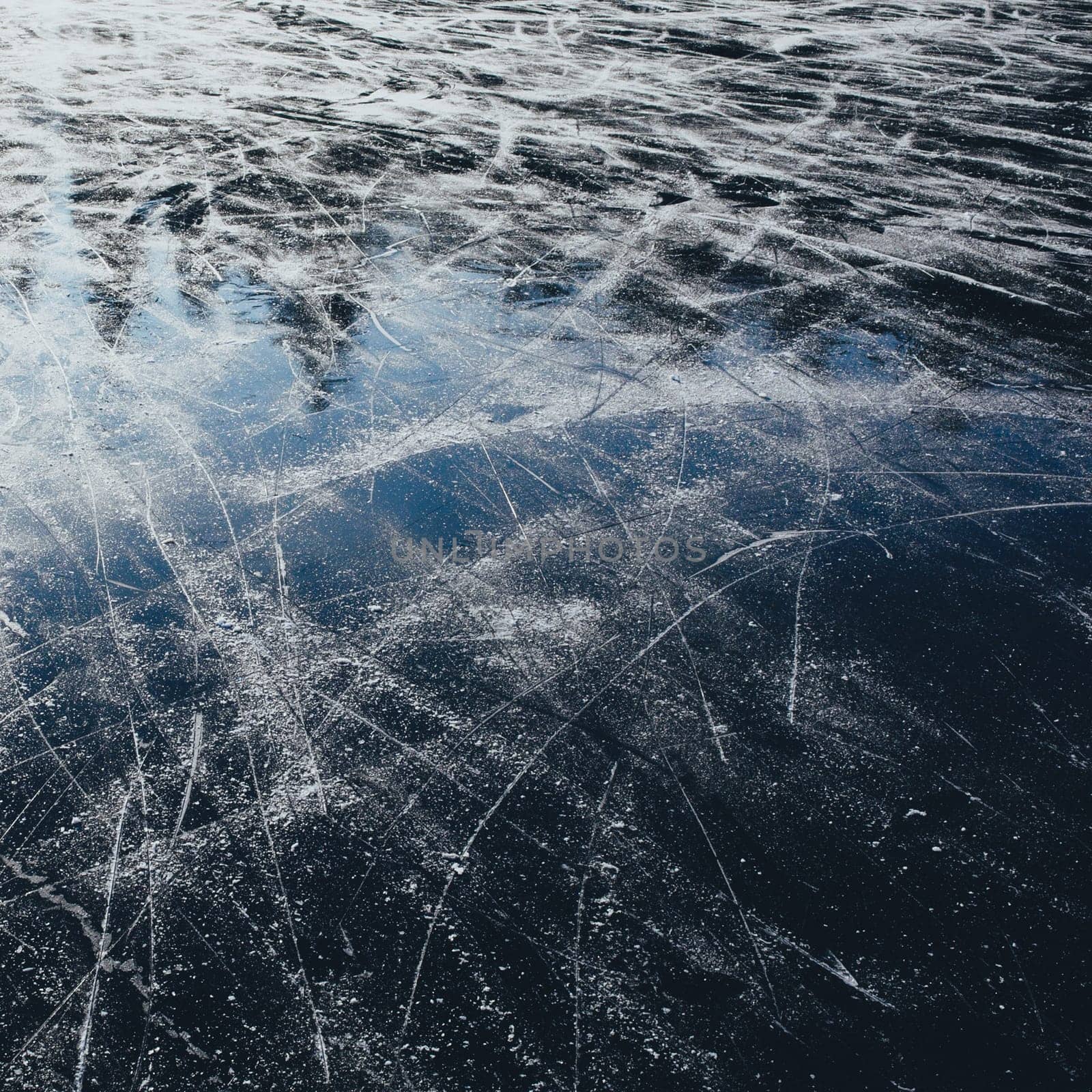 Surface of outdoor ice with snow, replete with skate marks. Abstract Ice background with focus on foreground