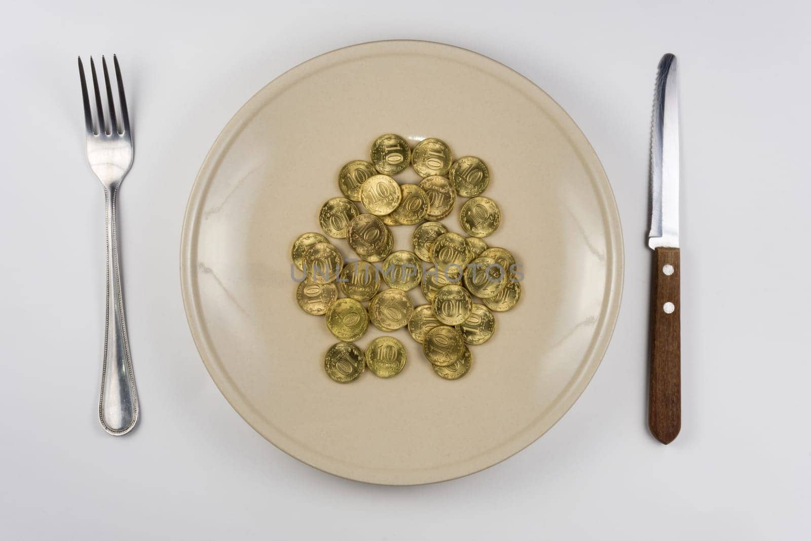 On the plate is a bunch of Russian ten-coin lying near tableware view from above