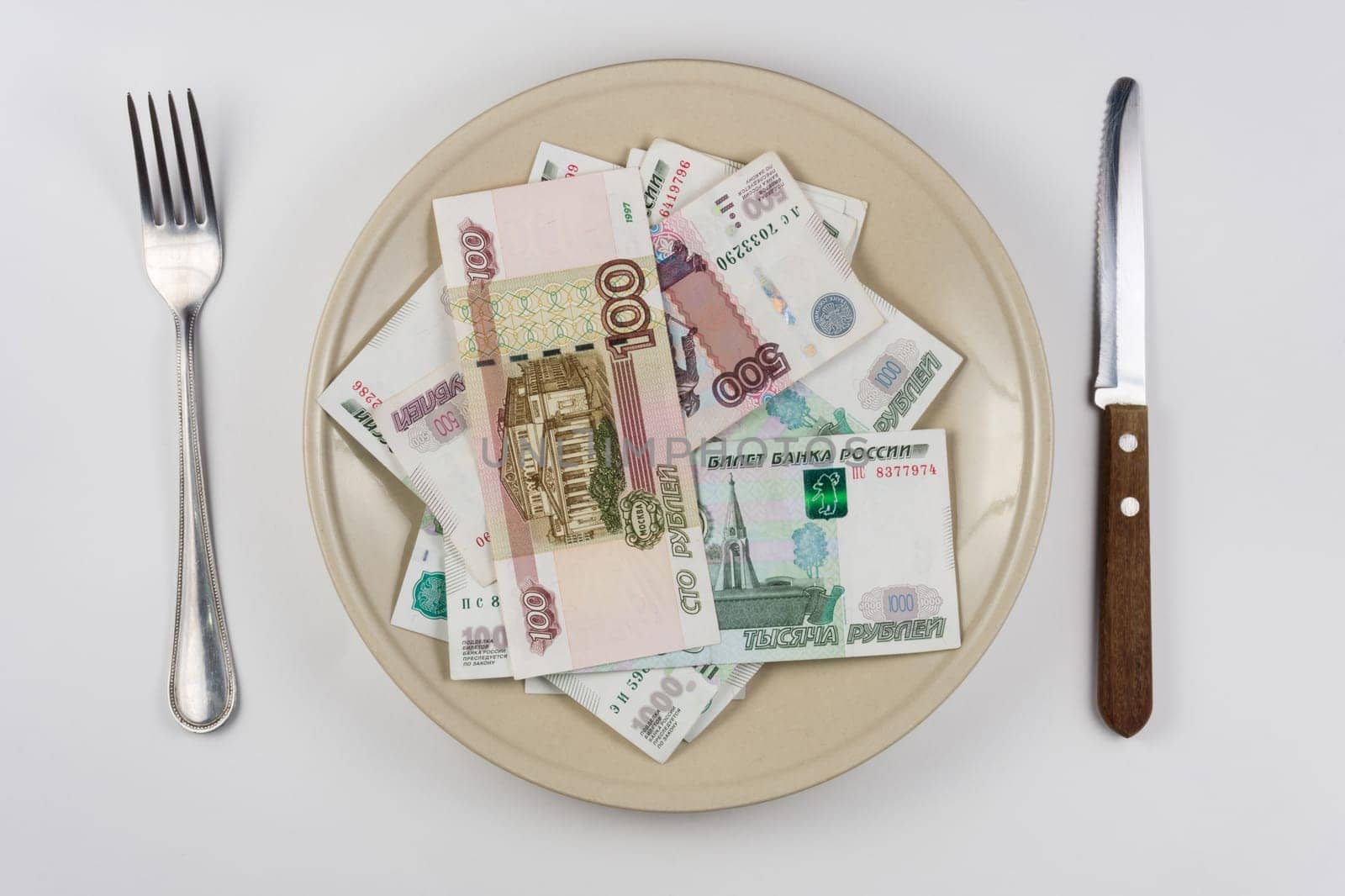 On the plate is a lot of money Russian rubles, lie next to utensils top view