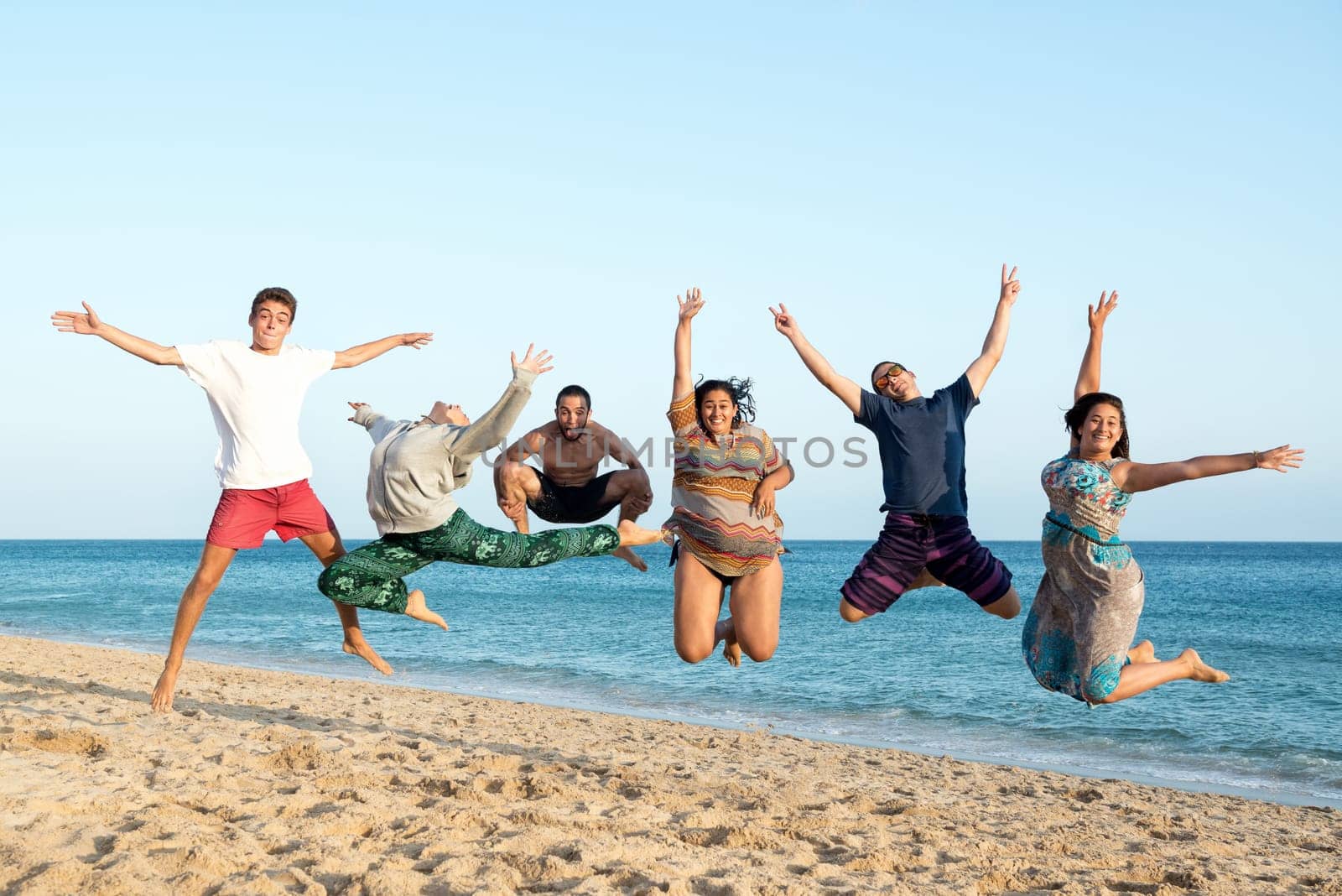 Group of happy teenage friends jumping at the beach