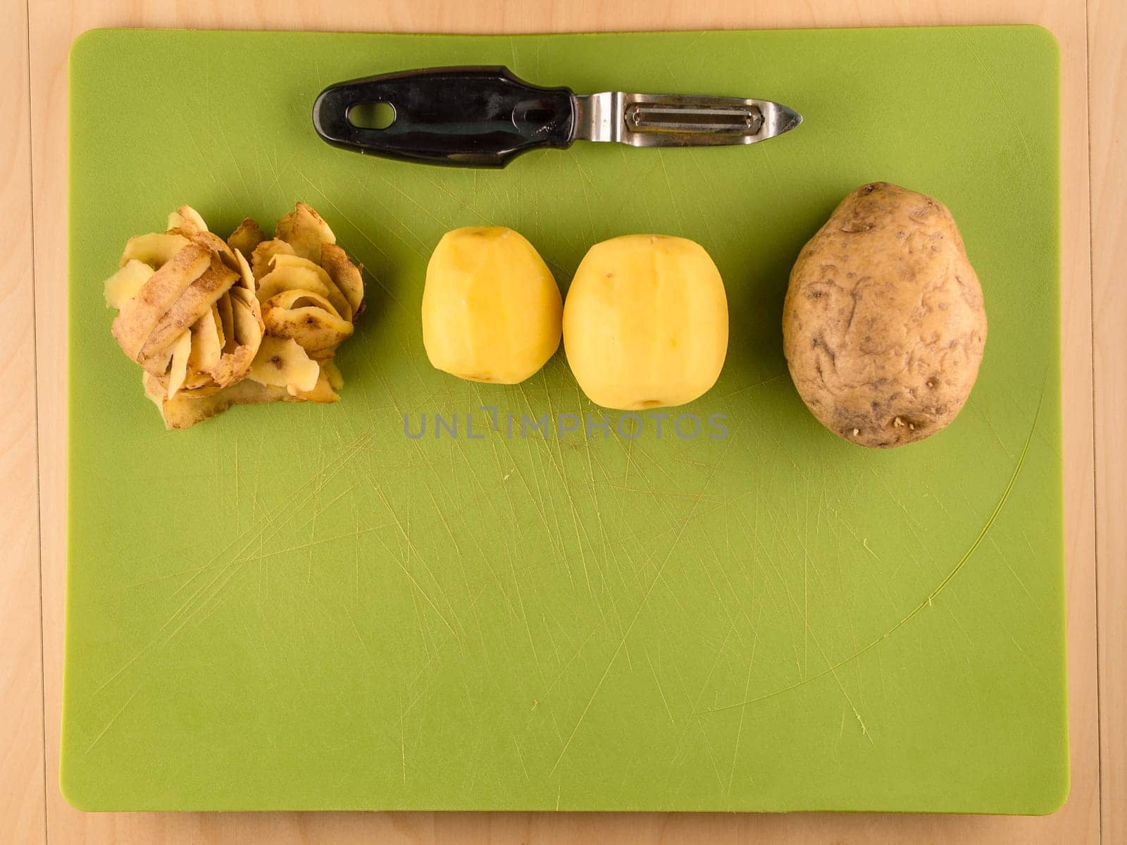 Pattern of sliced peeled potatoes on green used plastic board, simple food preparation illustration, vegetarian dieting, still life with center composition, close up