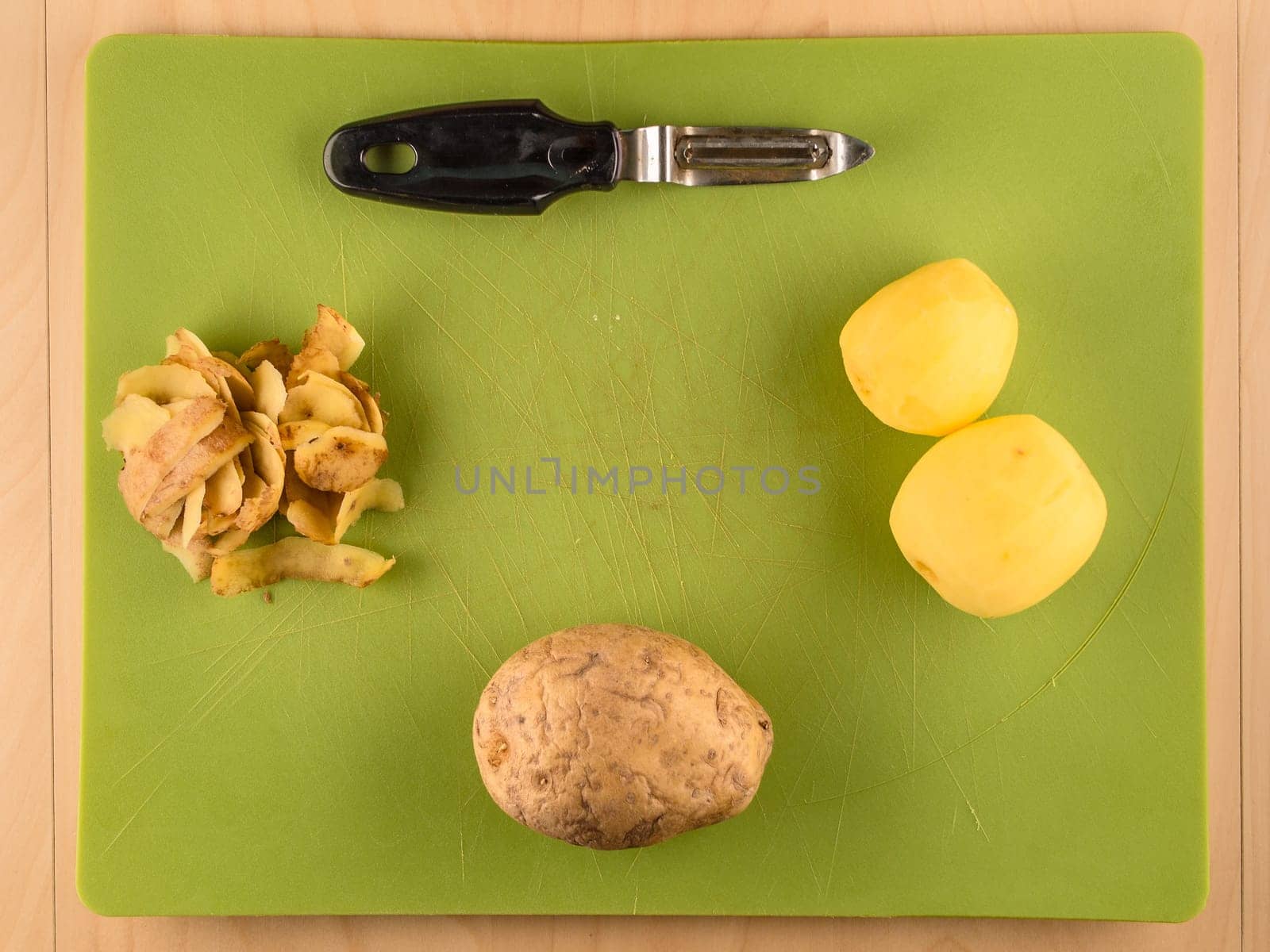 Pattern of sliced peeled potatoes on green used plastic board, simple food preparation illustration, vegetarian dieting, still life with center composition, close up
