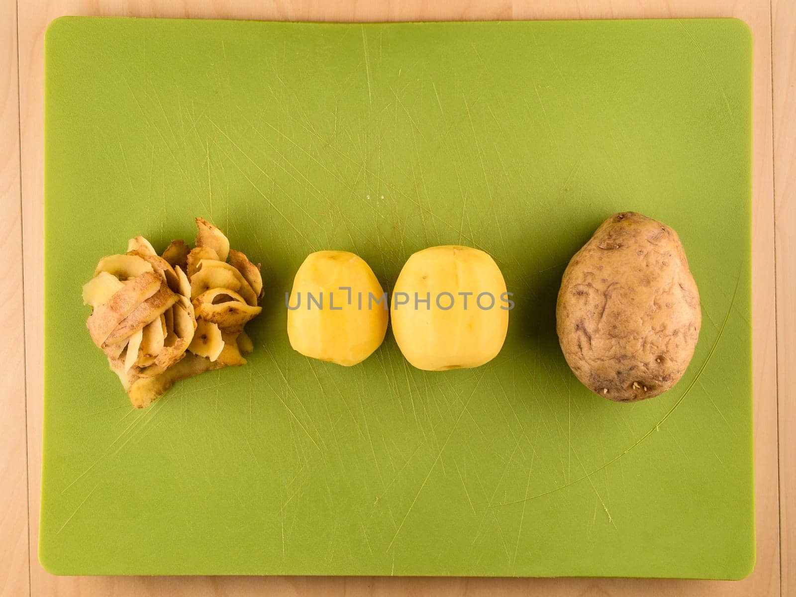 Pattern of sliced peeled potatoes on green used plastic board, simple food preparation illustration, vegetarian dieting, still life with center composition, close up