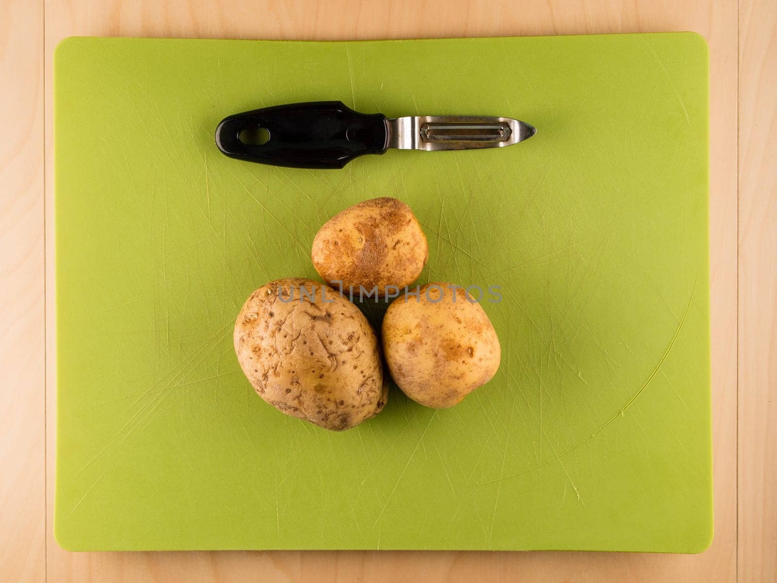 Pattern of sliced peeled potatoes on green used plastic board, simple food preparation illustration, vegetarian dieting, still life with center composition, close up