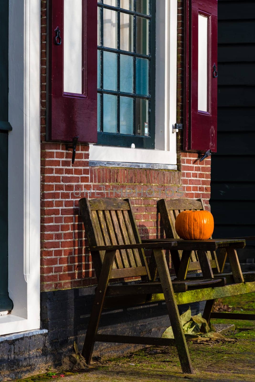 Pumpkin standing on vintage wooden table and chairs against brick wall, Halloween concept