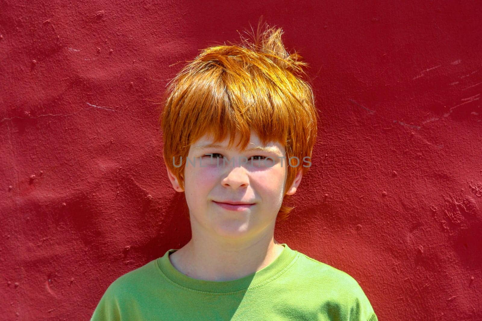 portrait of boy with red hair at a red wall