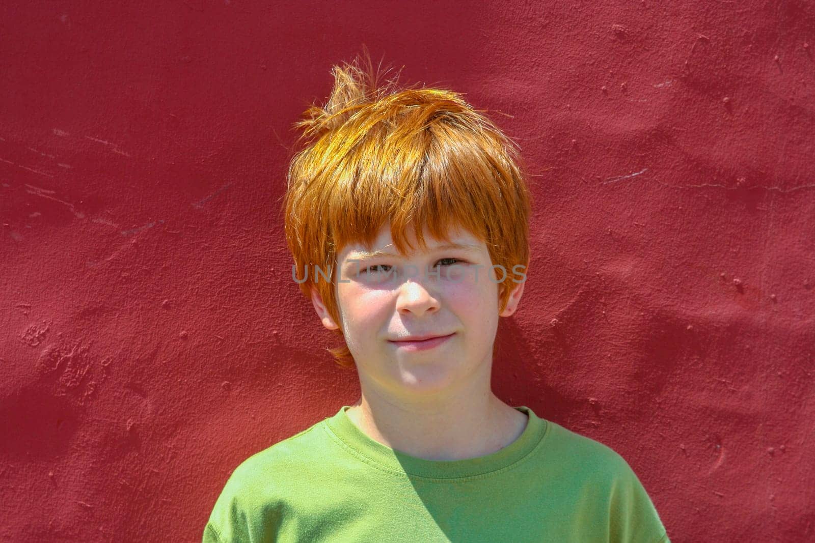 portrait of boy with red hair at a red wall