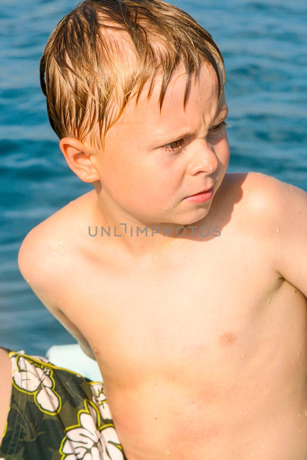 cute boy on a boat is angry and makes a grimace