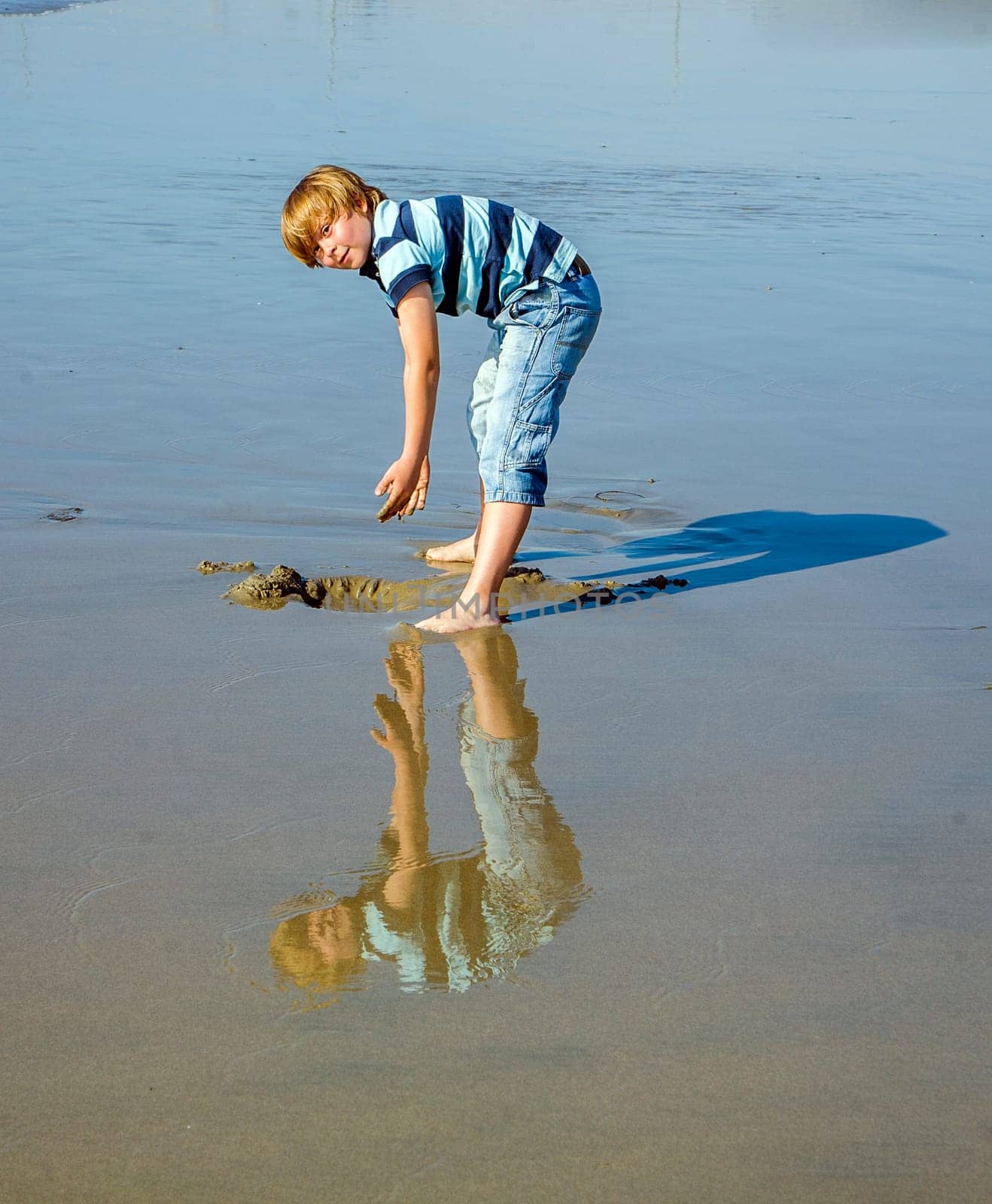 boy at the beach in Venice with reflecting picture in wet sand