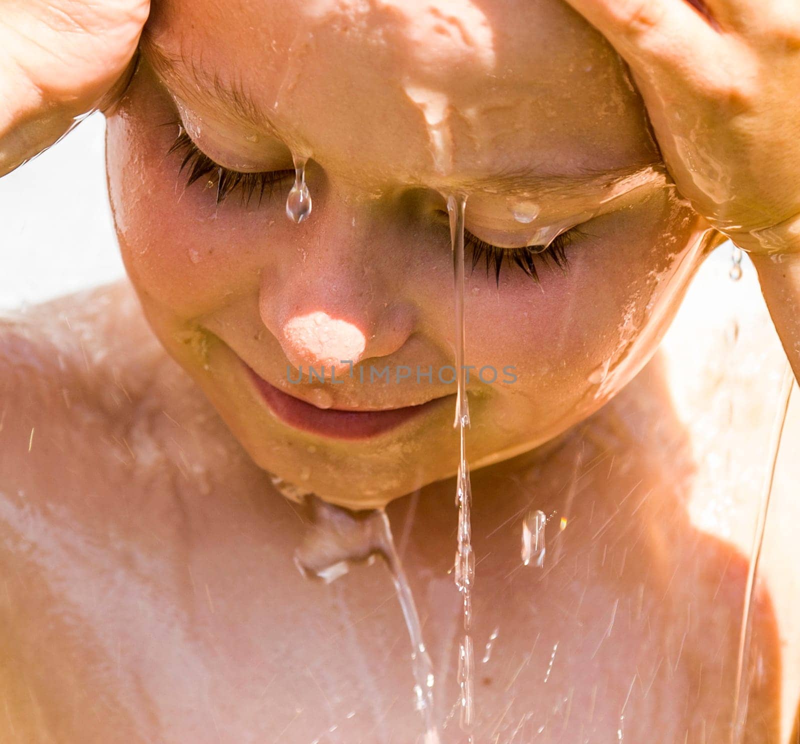 child has a refreshing shower in the garden