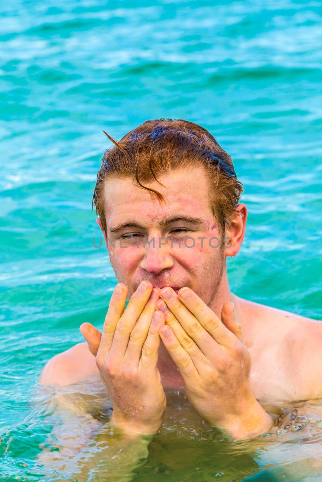 teenage boy cleans eyes of saltwater in the ocean
