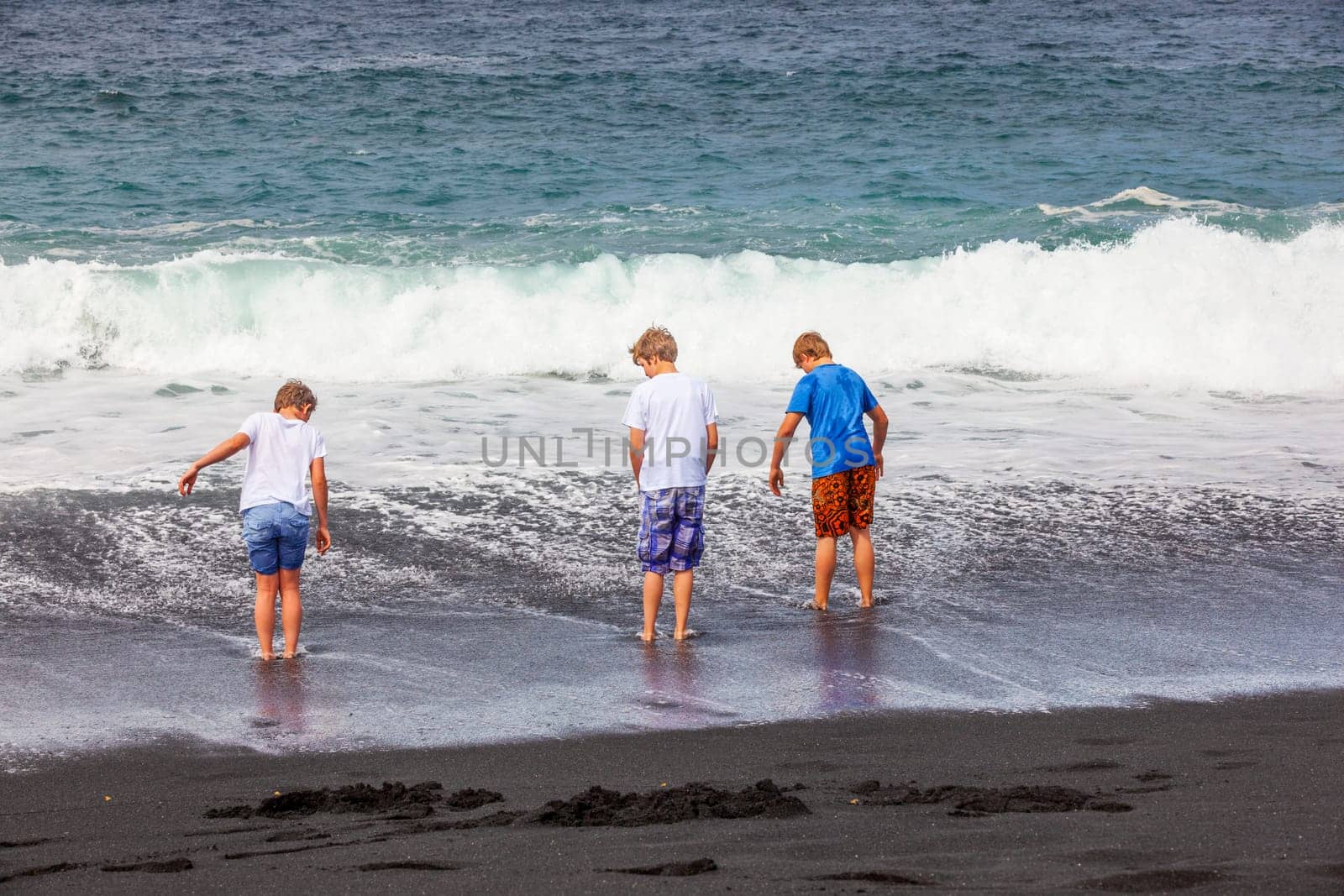 boys have fun at the black volcanic beach