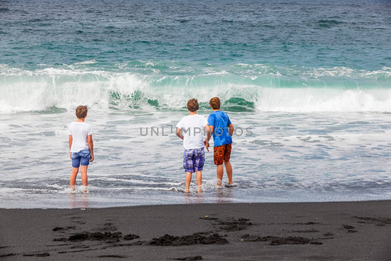 boys have fun at the black volcanic beach