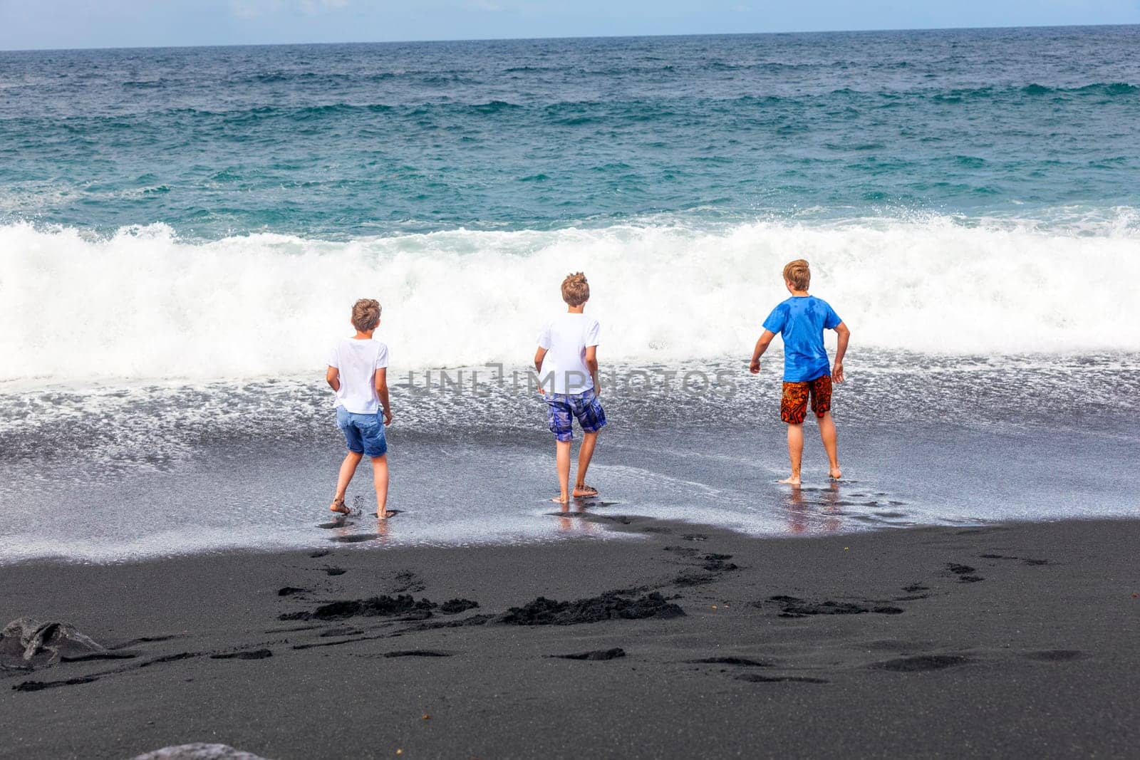 boys have fun at the black volcanic beach