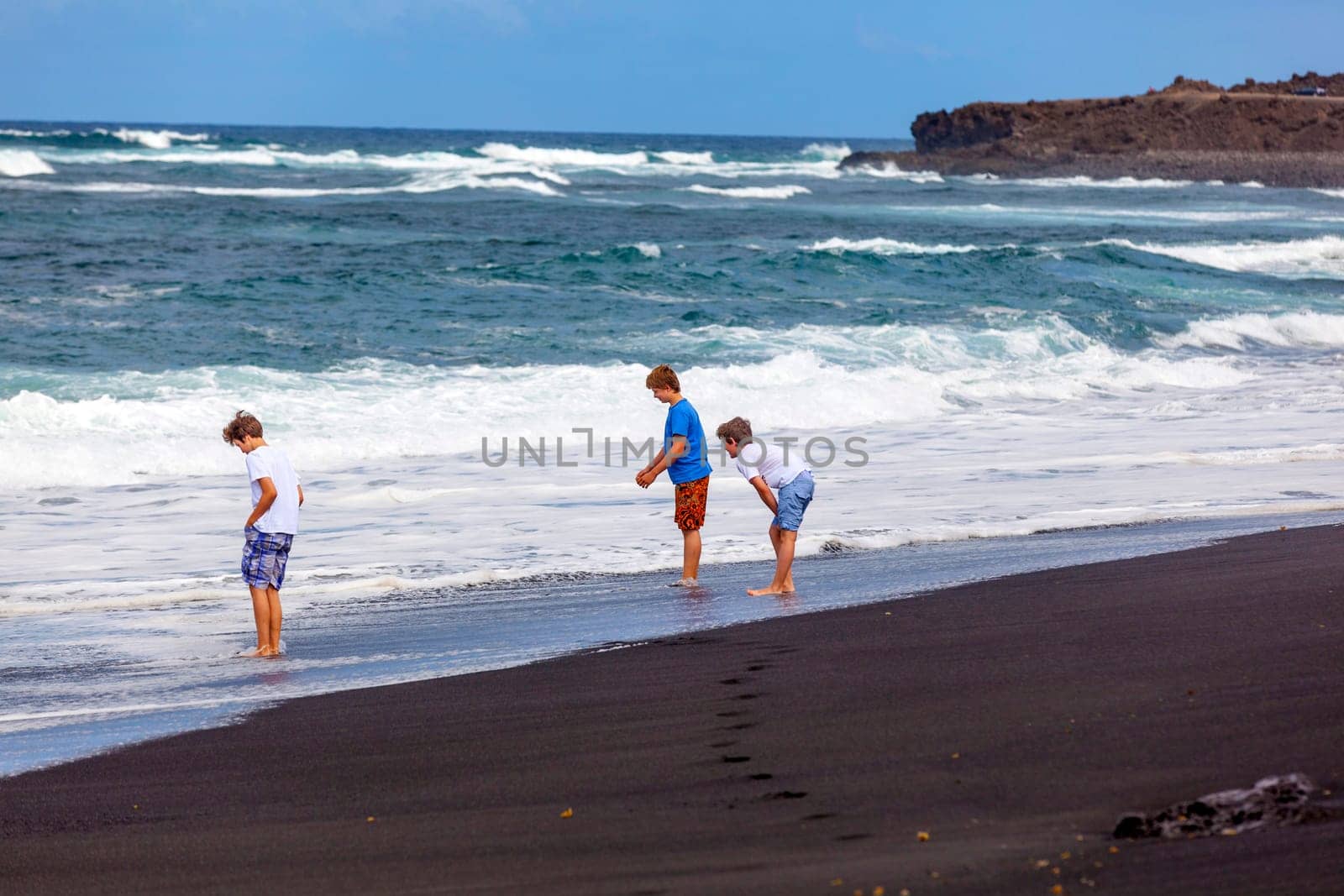 boys have fun at the black volcanic beach