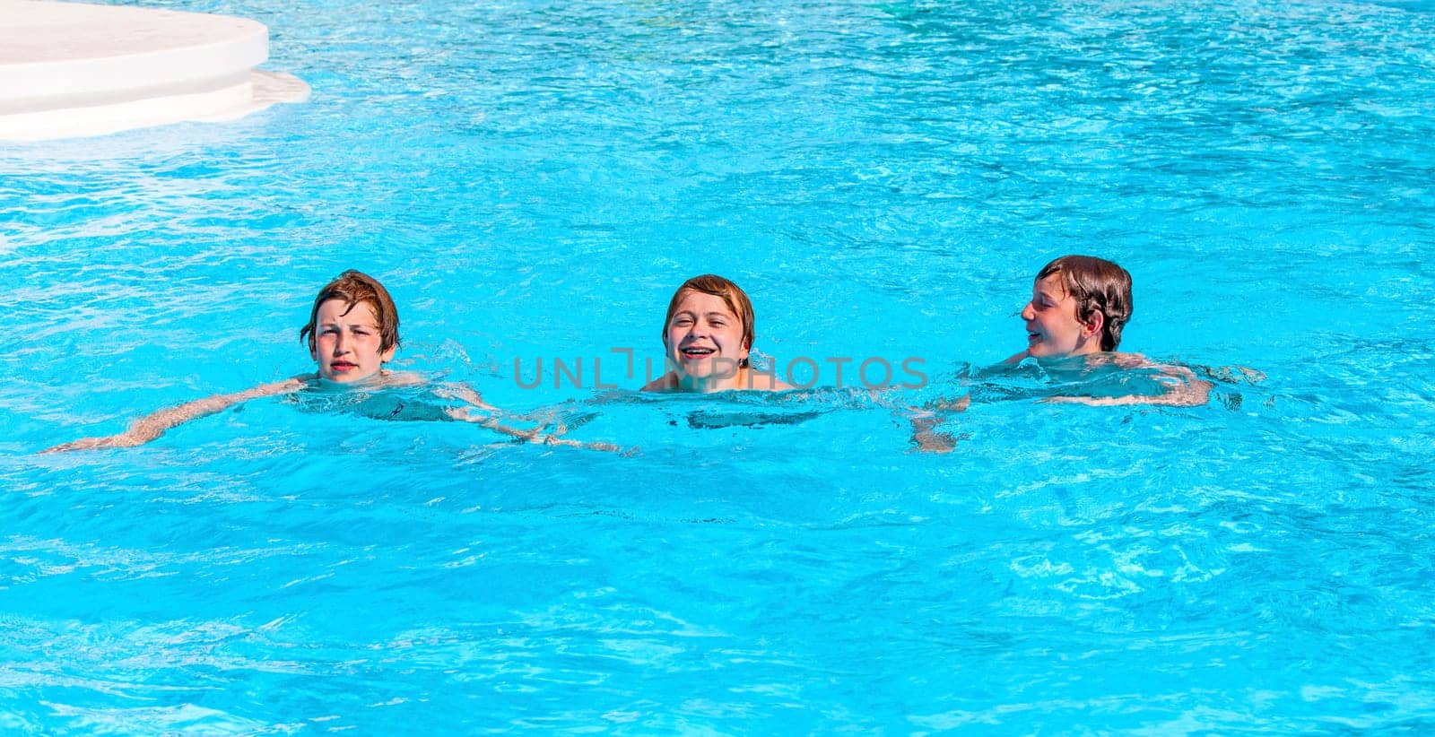 three friends swimming in a row in the pool