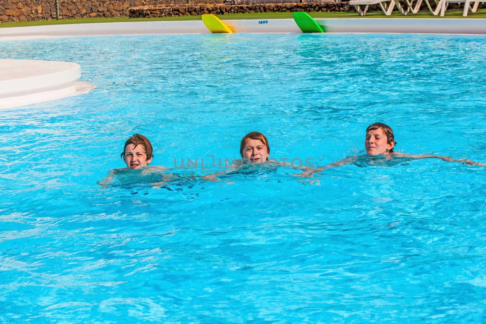 three friends swimming in a row in the pool