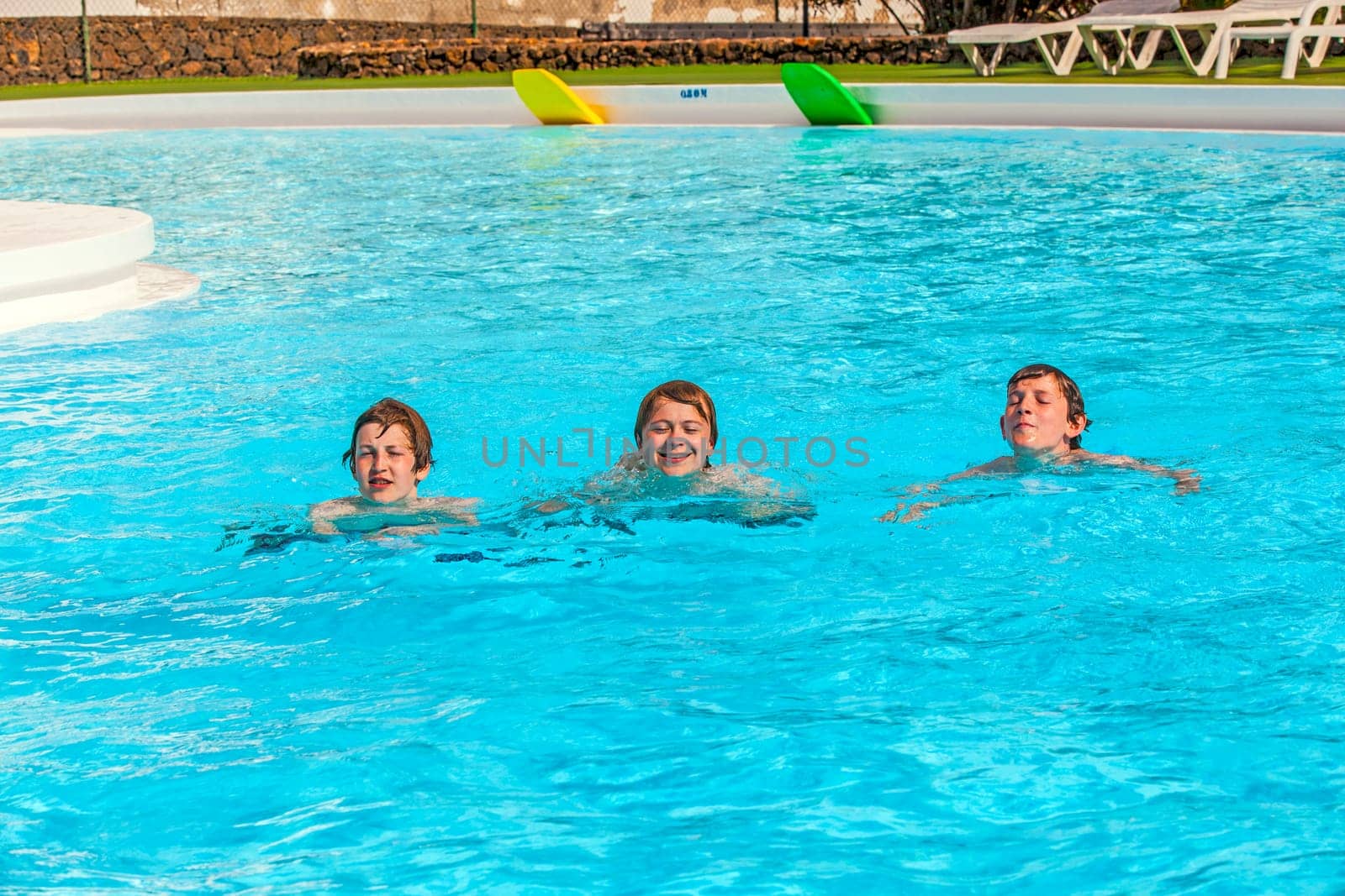 three friends swimming in a row in the pool