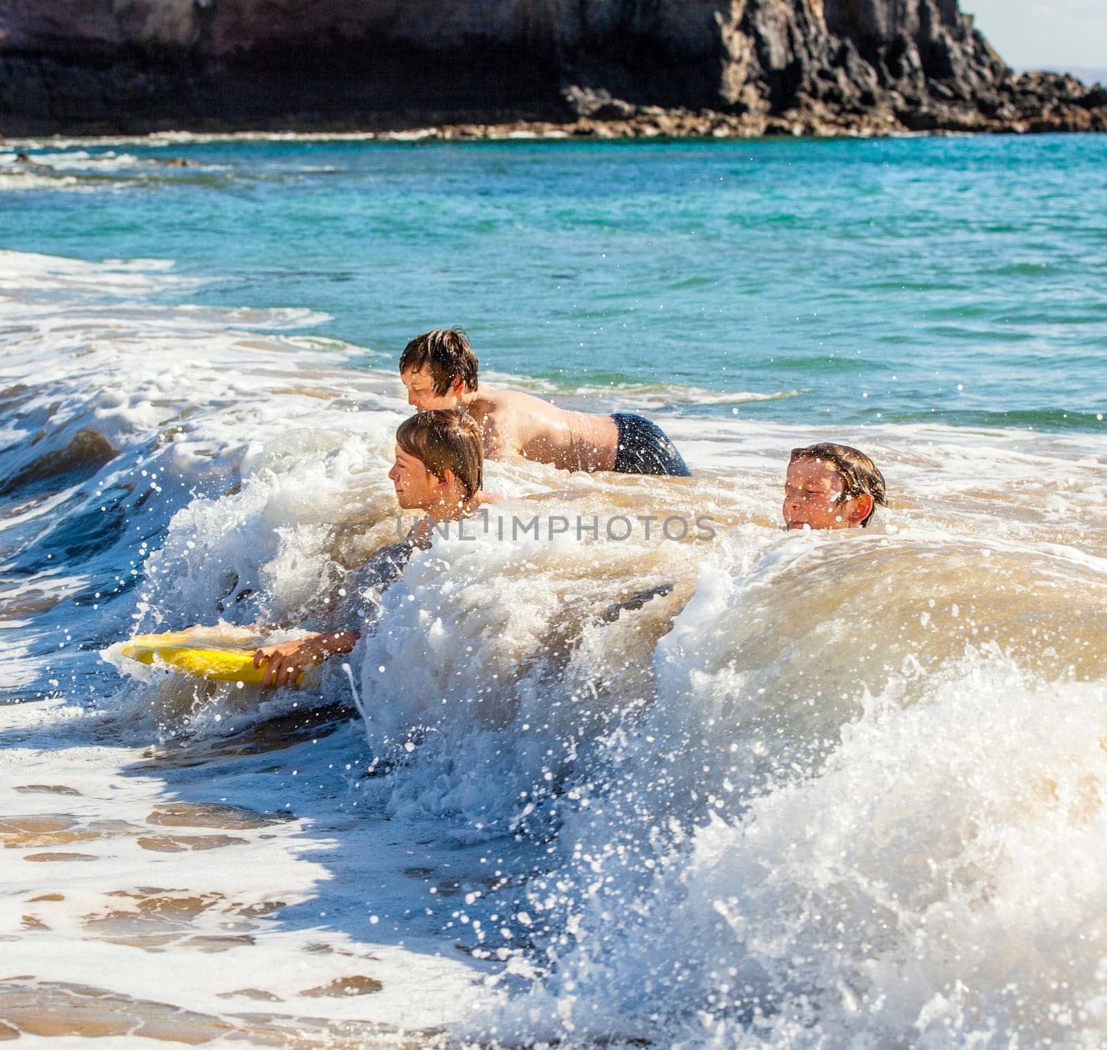 boys have fun riding in the waves