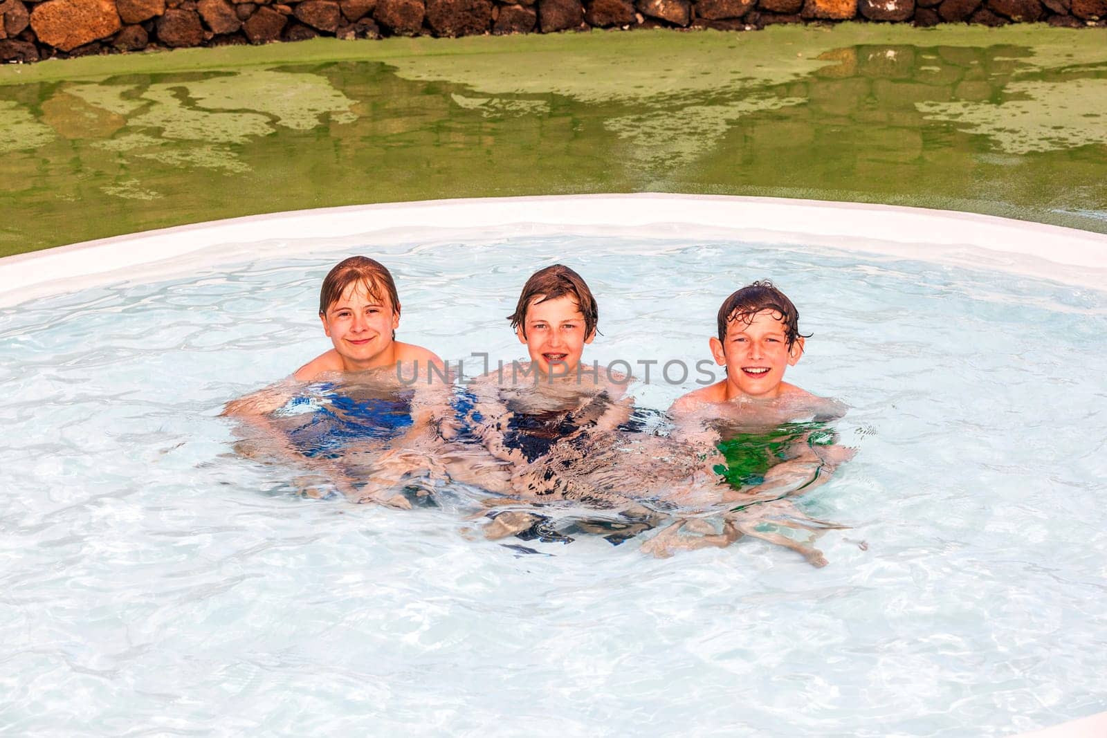 three friends have fun joking in the pool