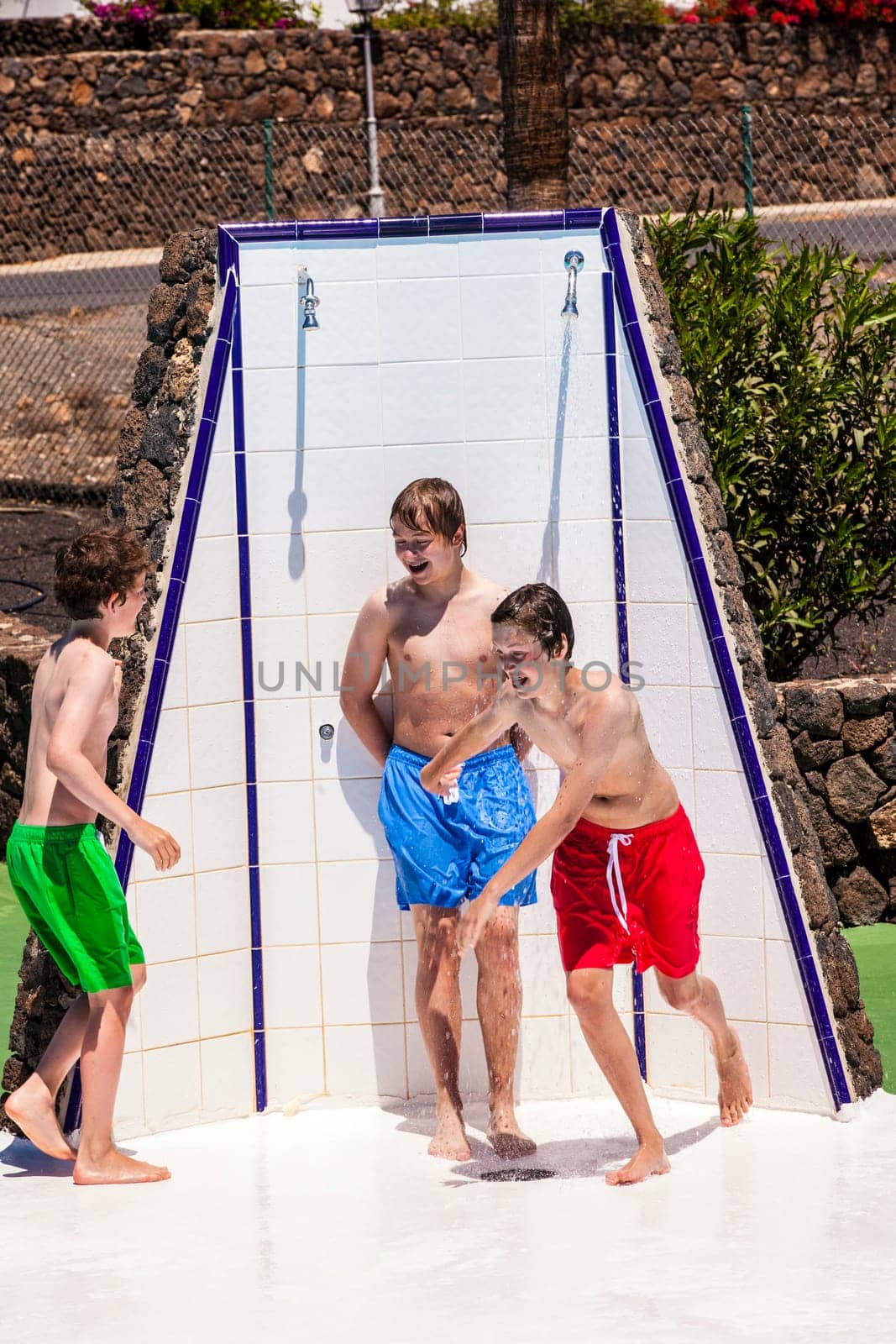 cute boys have fun unter the pool shower