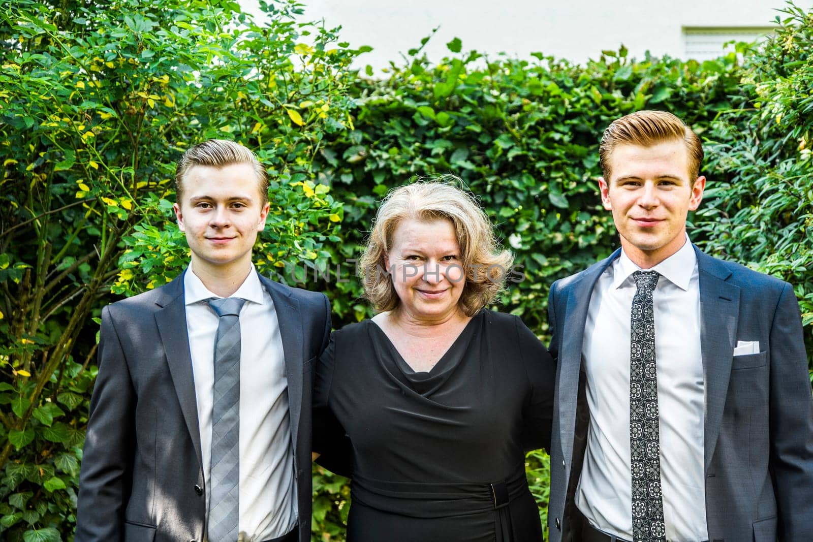 portrait of mother with her two adolescent sons, dressed in suit with tie