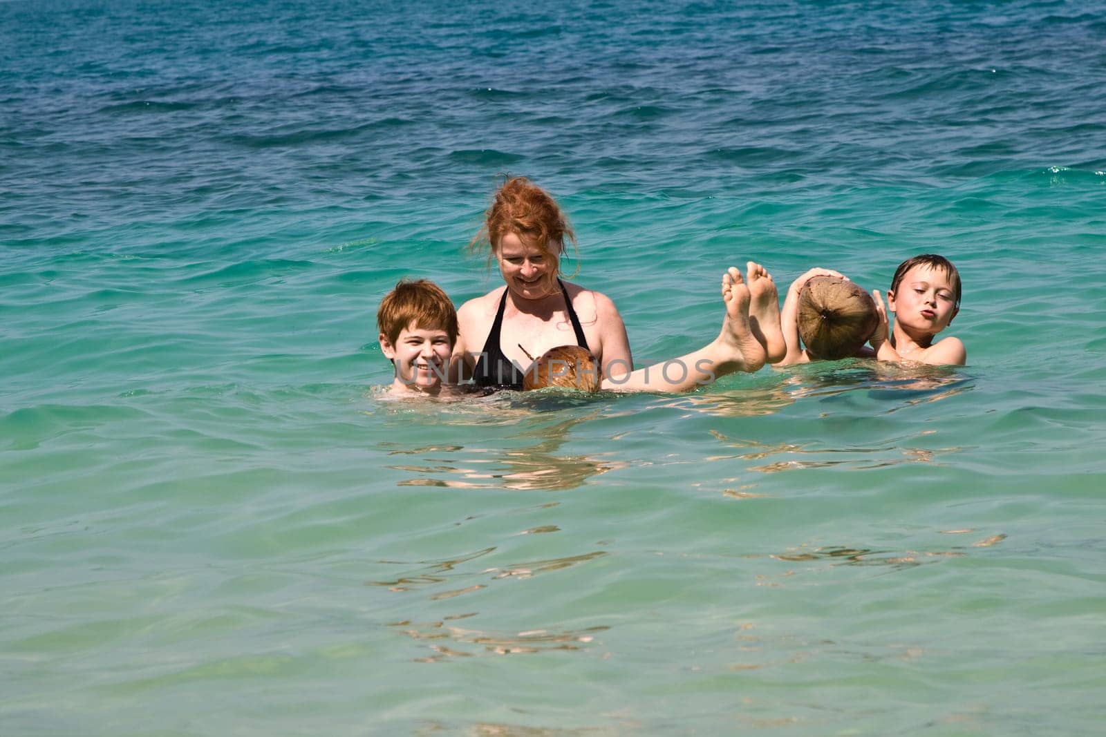 family  is playing with a coconut in the sea on a beautiful beach