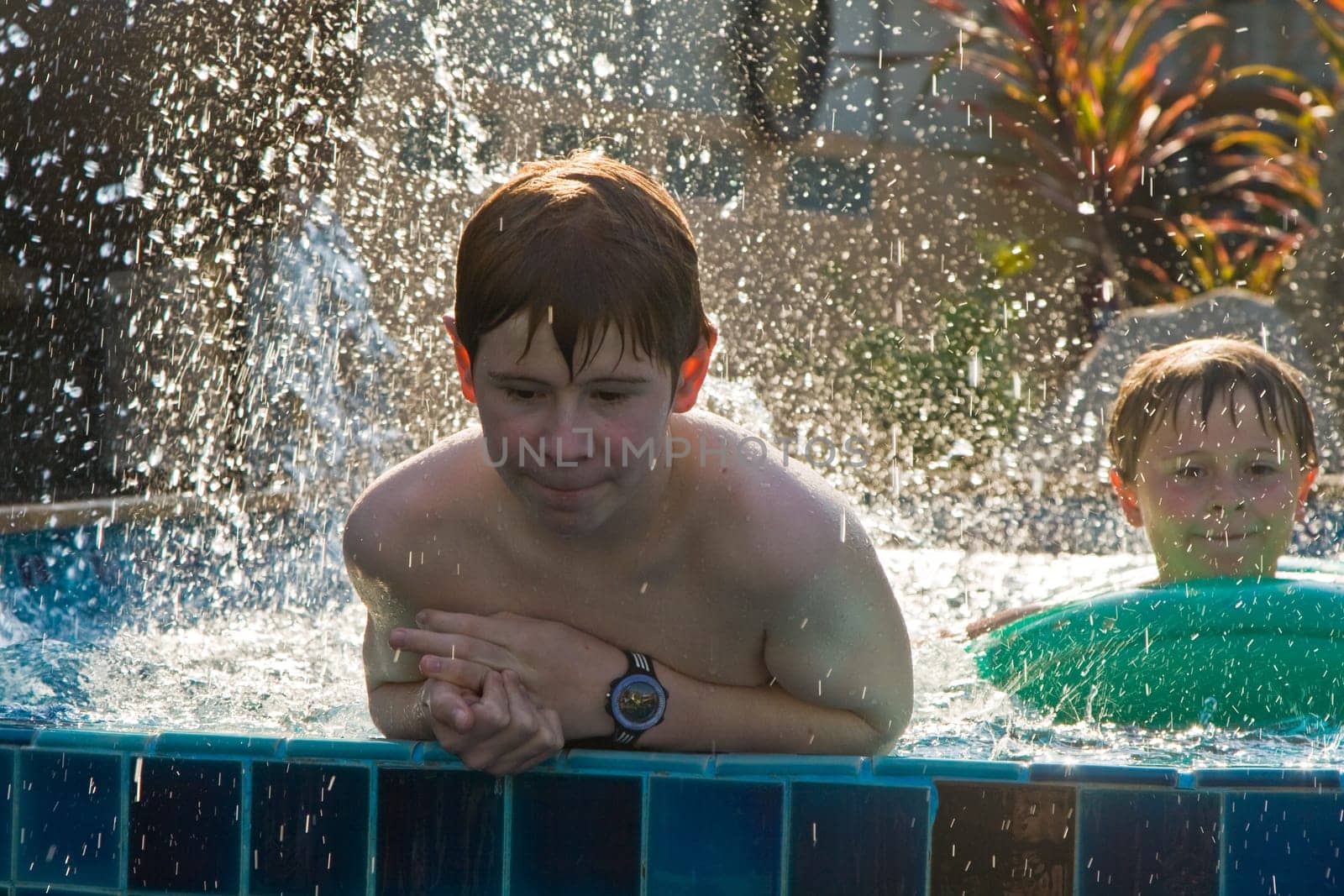 children are playing in a pool and spottering with water