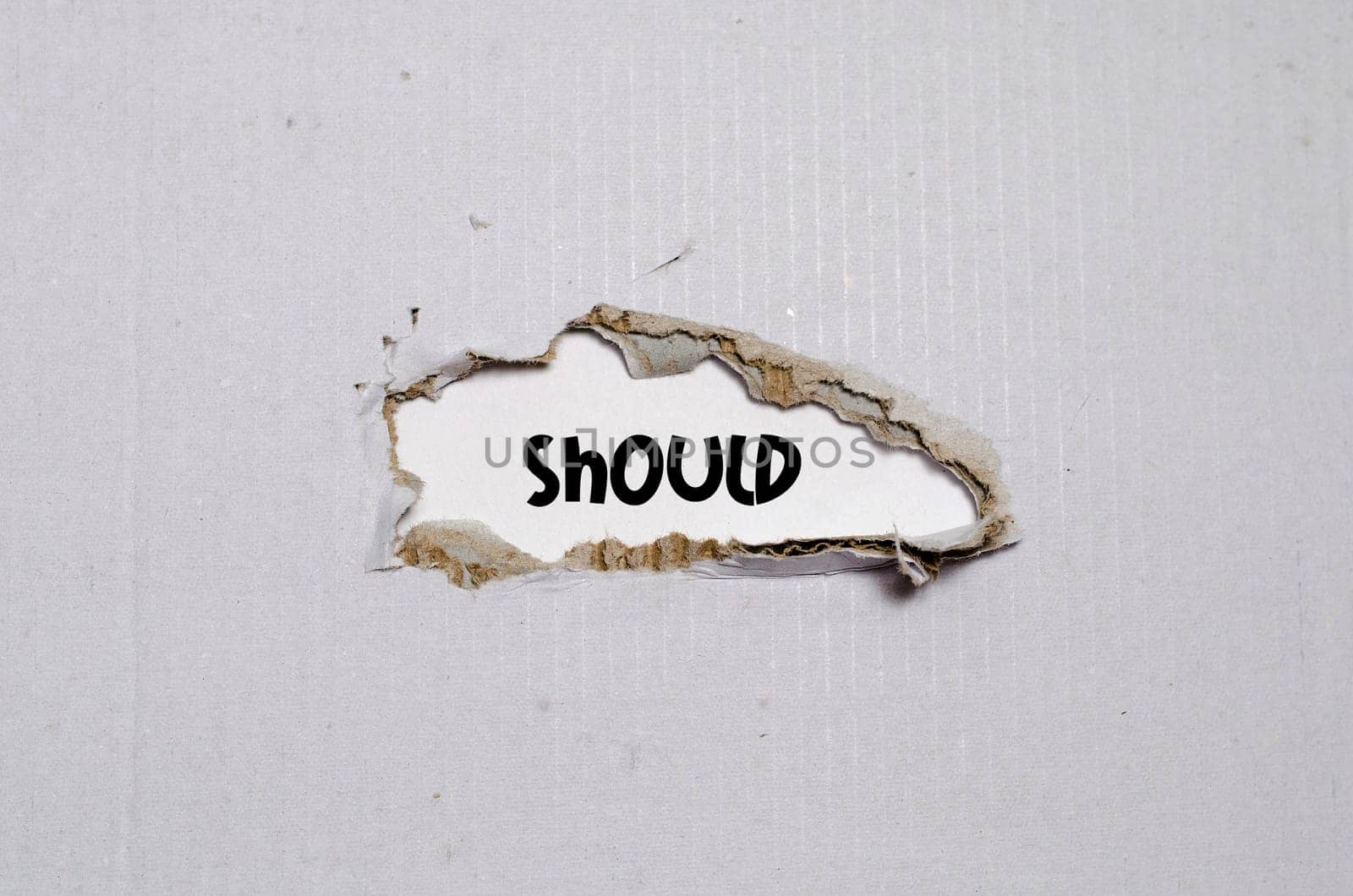 The word should appearing behind torn paper