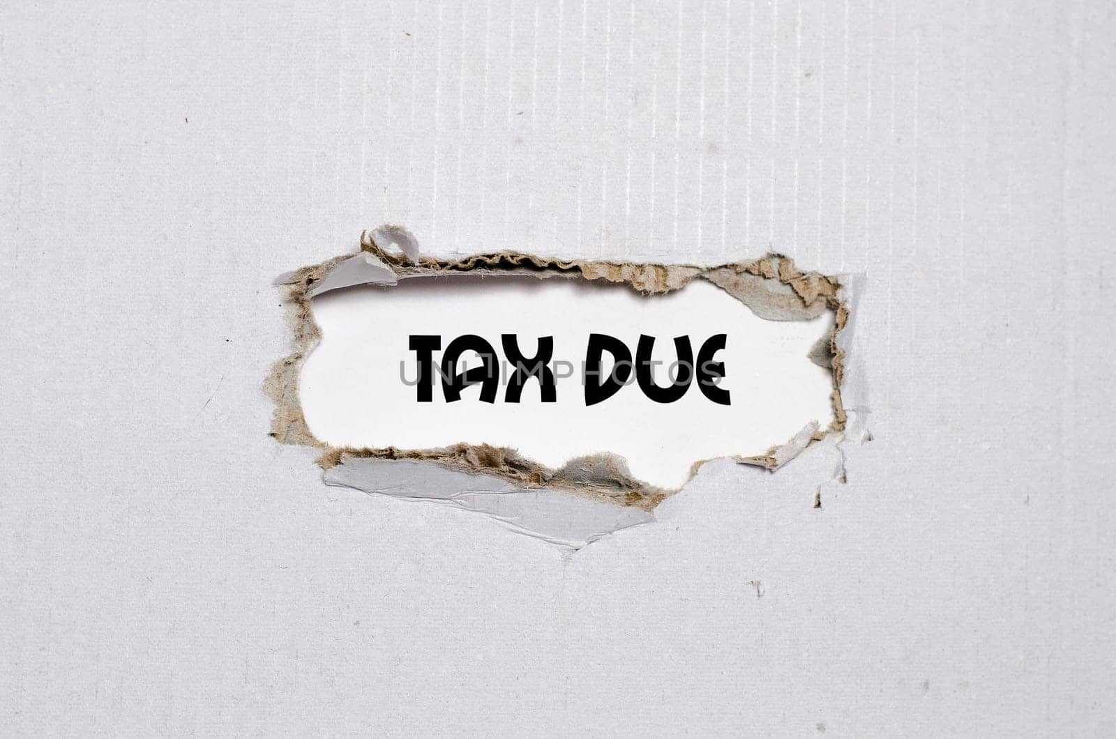 The word tax due appearing behind torn paper