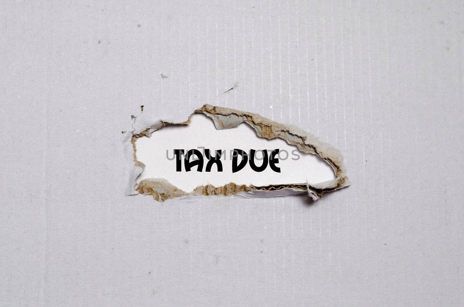 The word tax due appearing behind torn paper