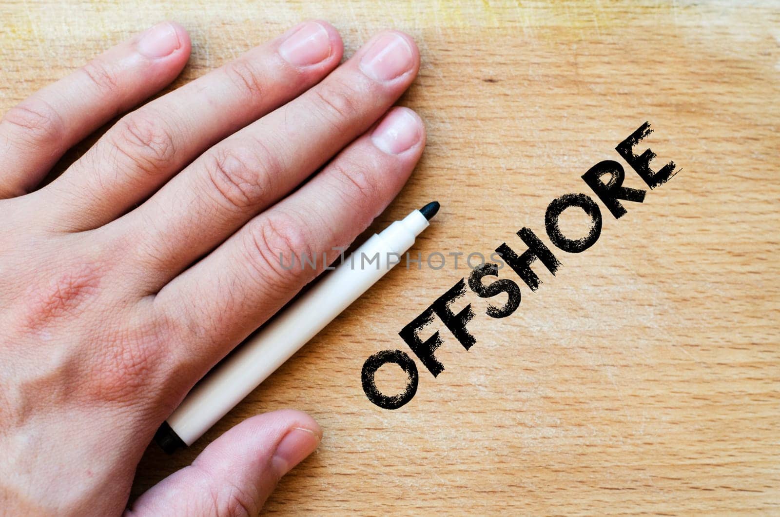 Human hand over wooden background and offshore text concept