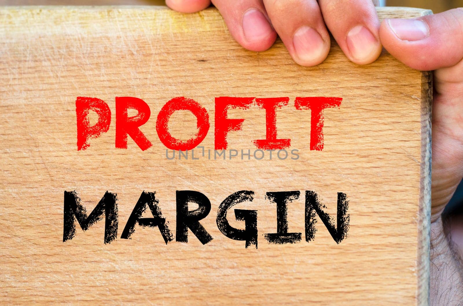 Human hand over wooden background and profit margin text concept