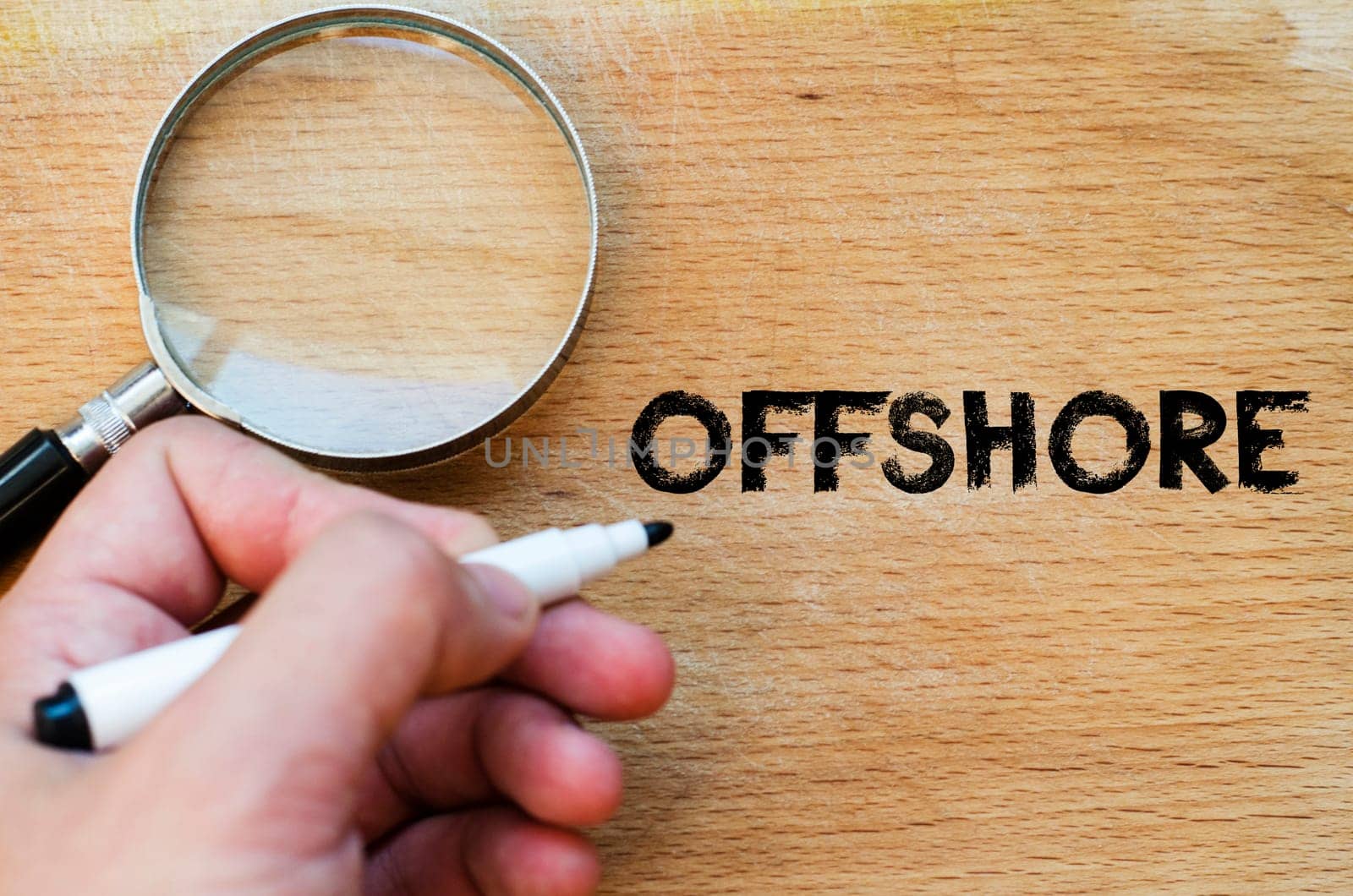 Human hand over wooden background and offshore text concept