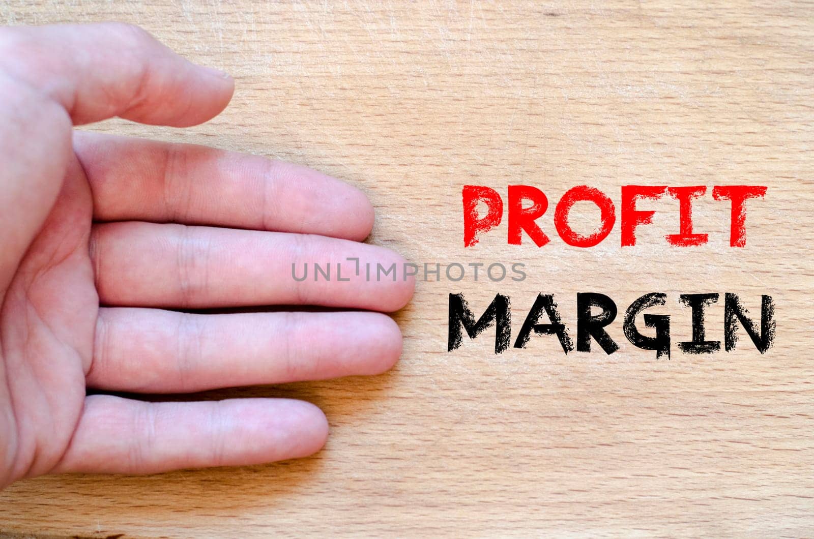 Human hand over wooden background and profit margin text concept