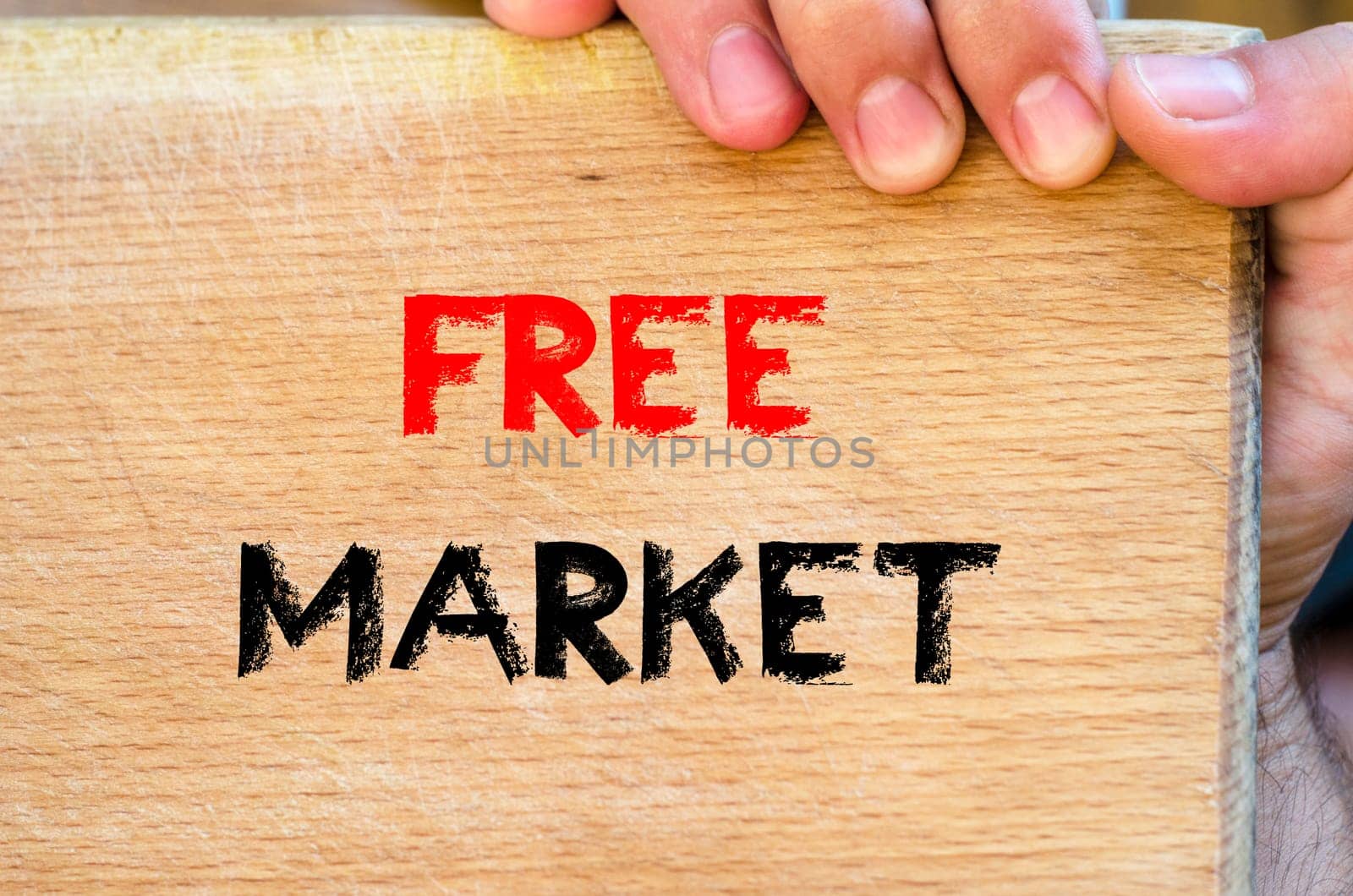 Human hand over wooden background and free market text concept