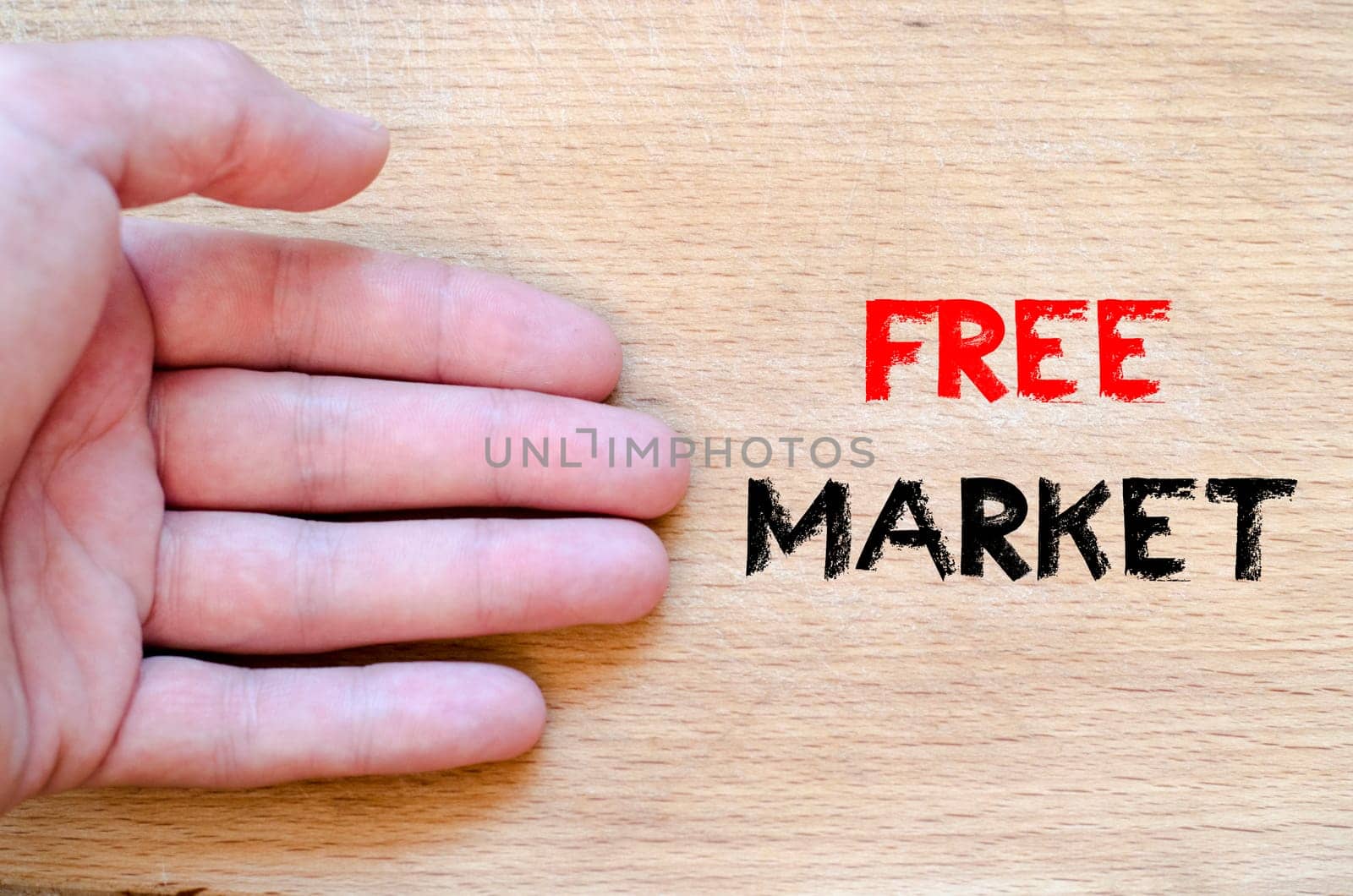 Human hand over wooden background and free market text concept