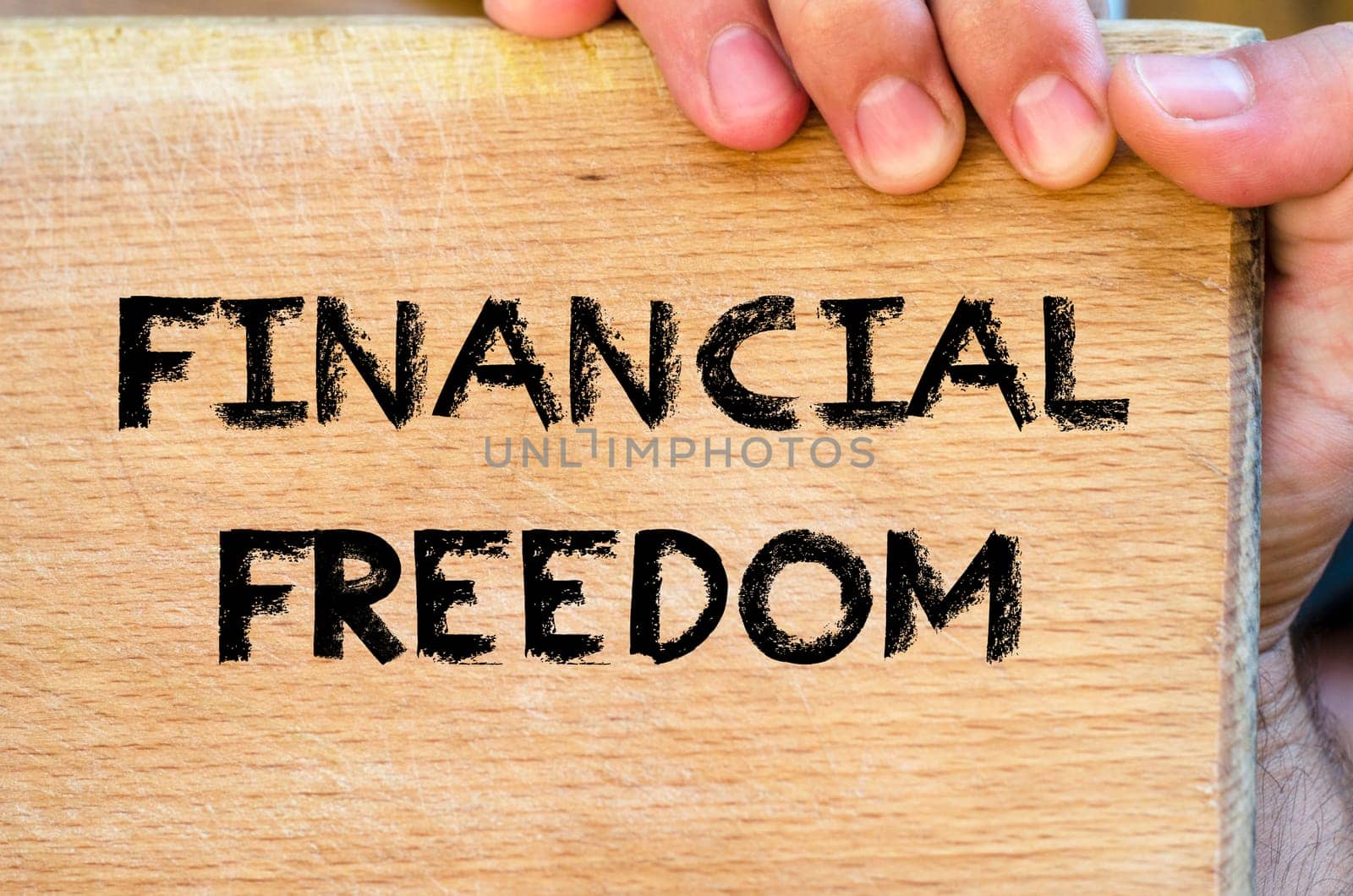 Human hand over wooden background and financial freedom text concept