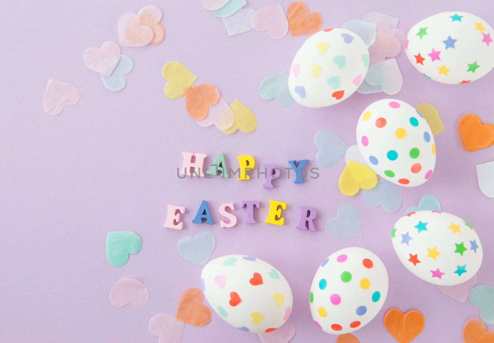 Colorful Easter eggs on purple background with heart confetti
