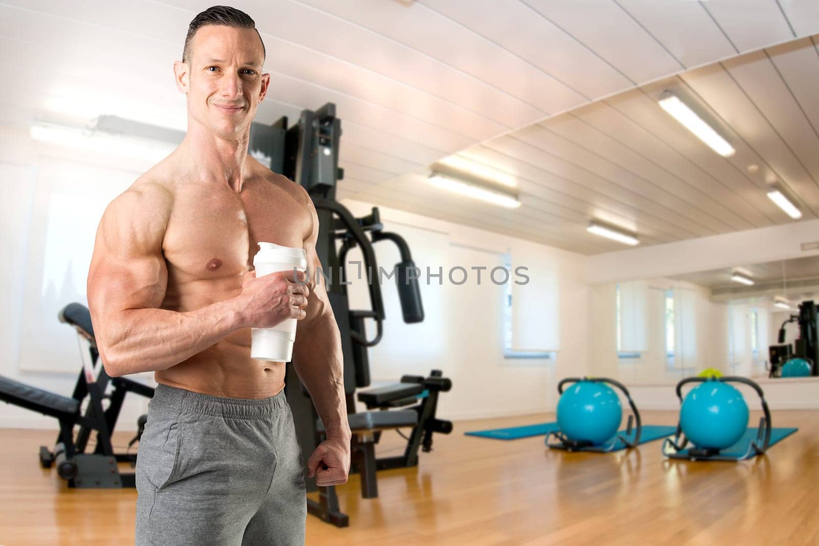 Powerful athletic man with great physique holding a gym bottle