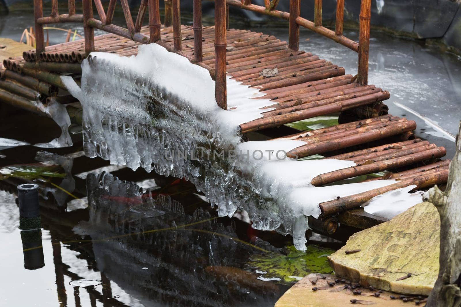 Icicles hang from a bridge over a frozen lake.