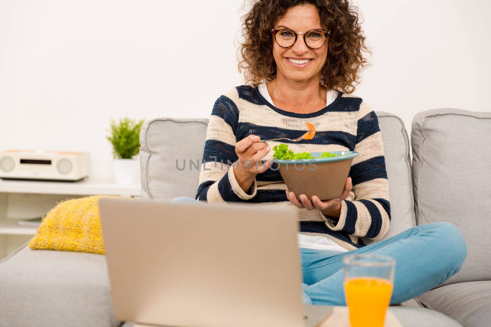 Beautiful woman at home sitting on the sofa working and eating a apple