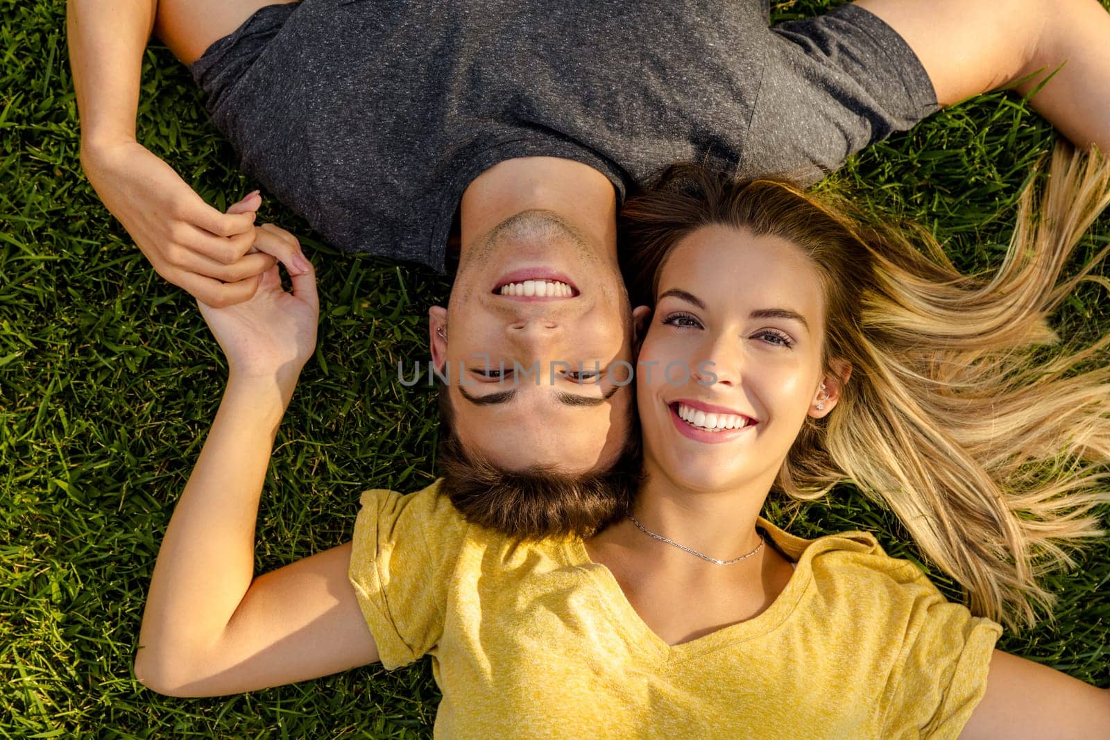 Portrait of a young beautiful couple lying on the grass