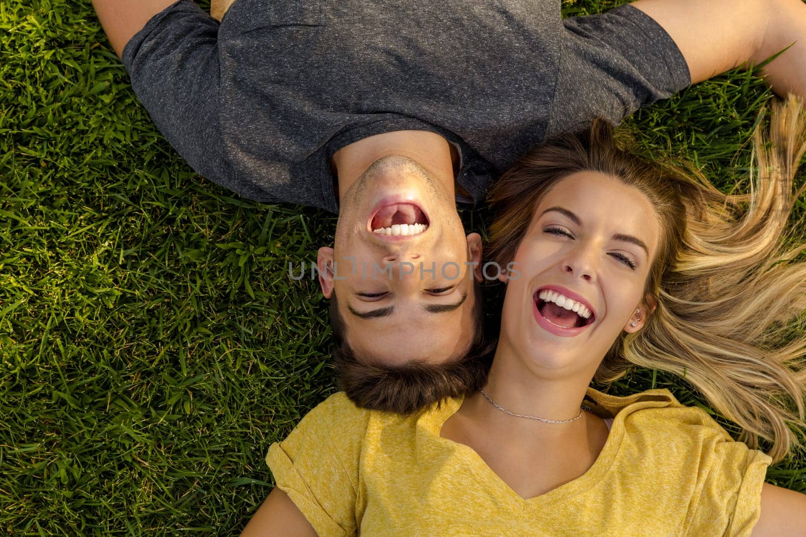 Portrait of a young beautiful couple lying on the grass