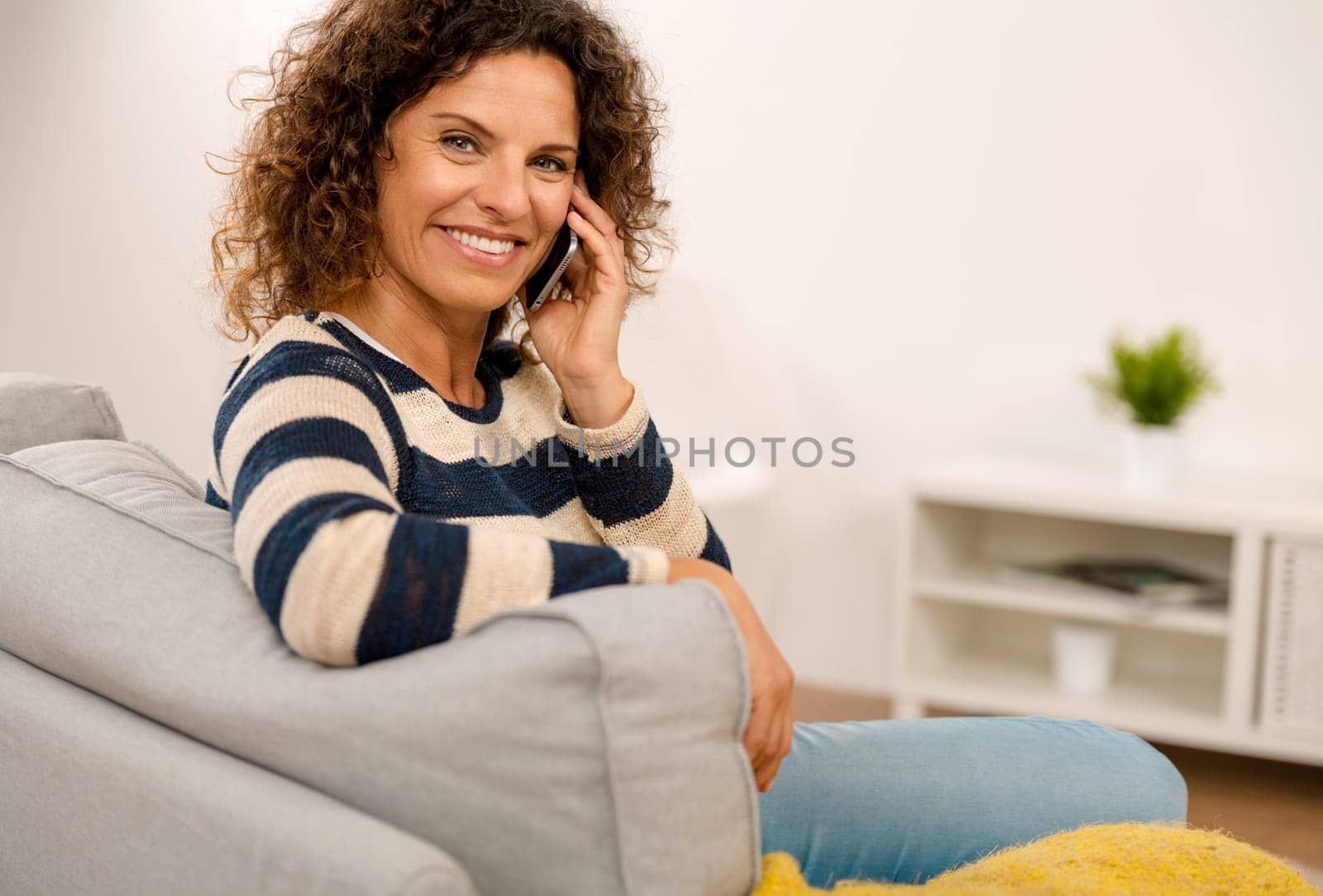 Top view of a beautiful woman on the sofa sending a text message