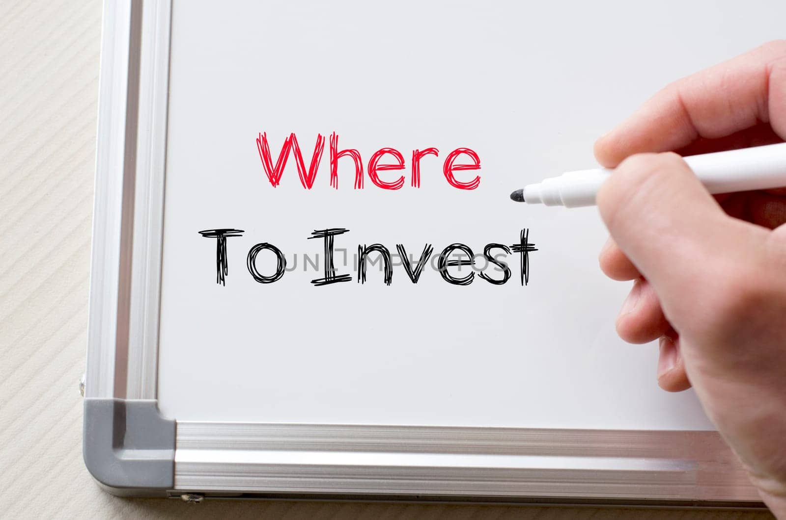 Human hand writing where to invest on whiteboard