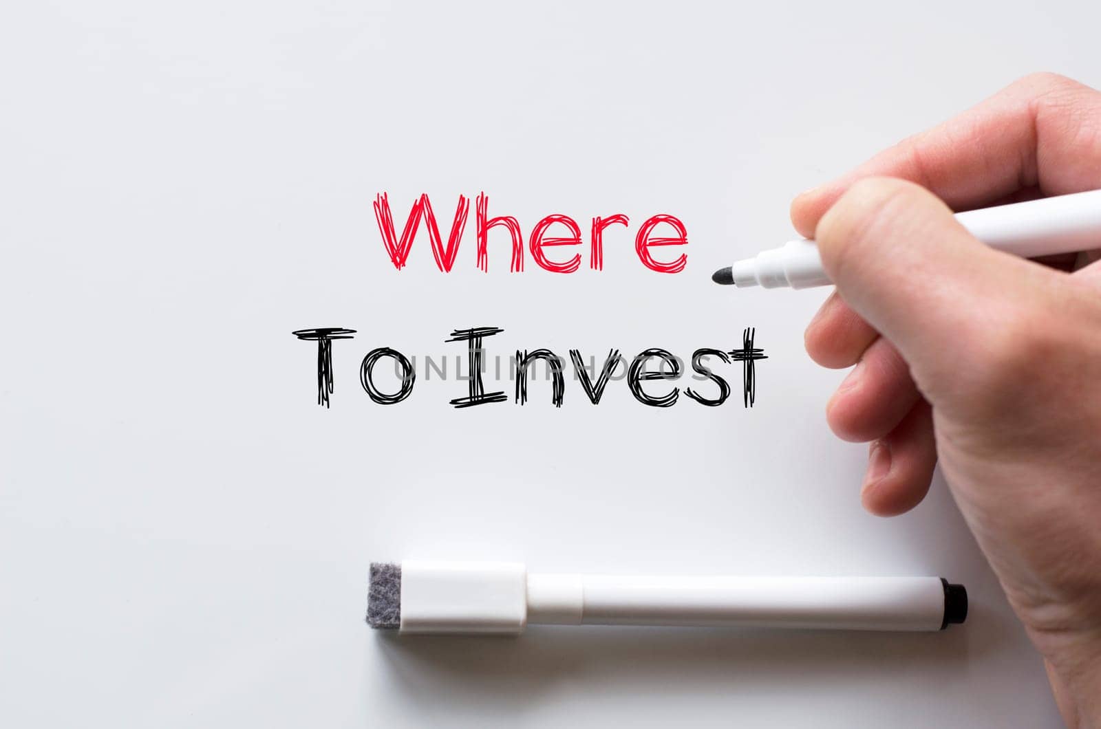 Human hand writing where to invest on whiteboard